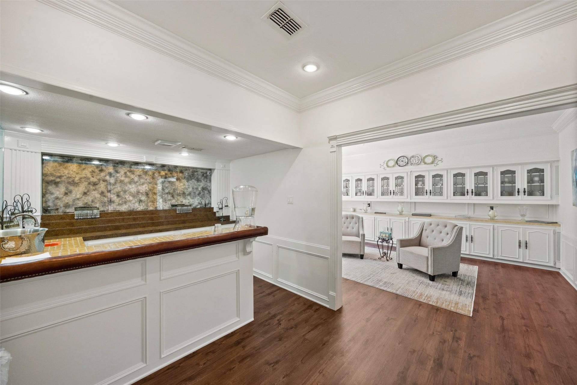 Interior passage featuring a long counter, lower cabinetry, and an opening to a bright adjoining sitting area.