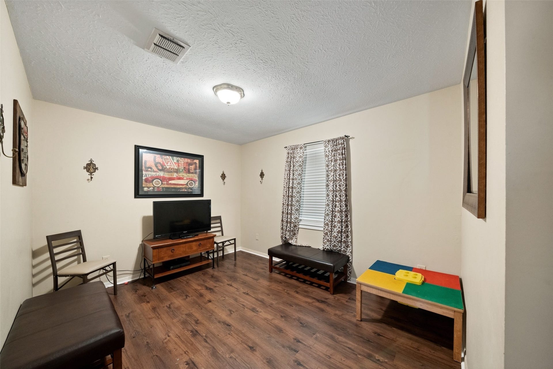 Additional guest house room featuring wood flooring, neutral walls, and windows providing natural light.