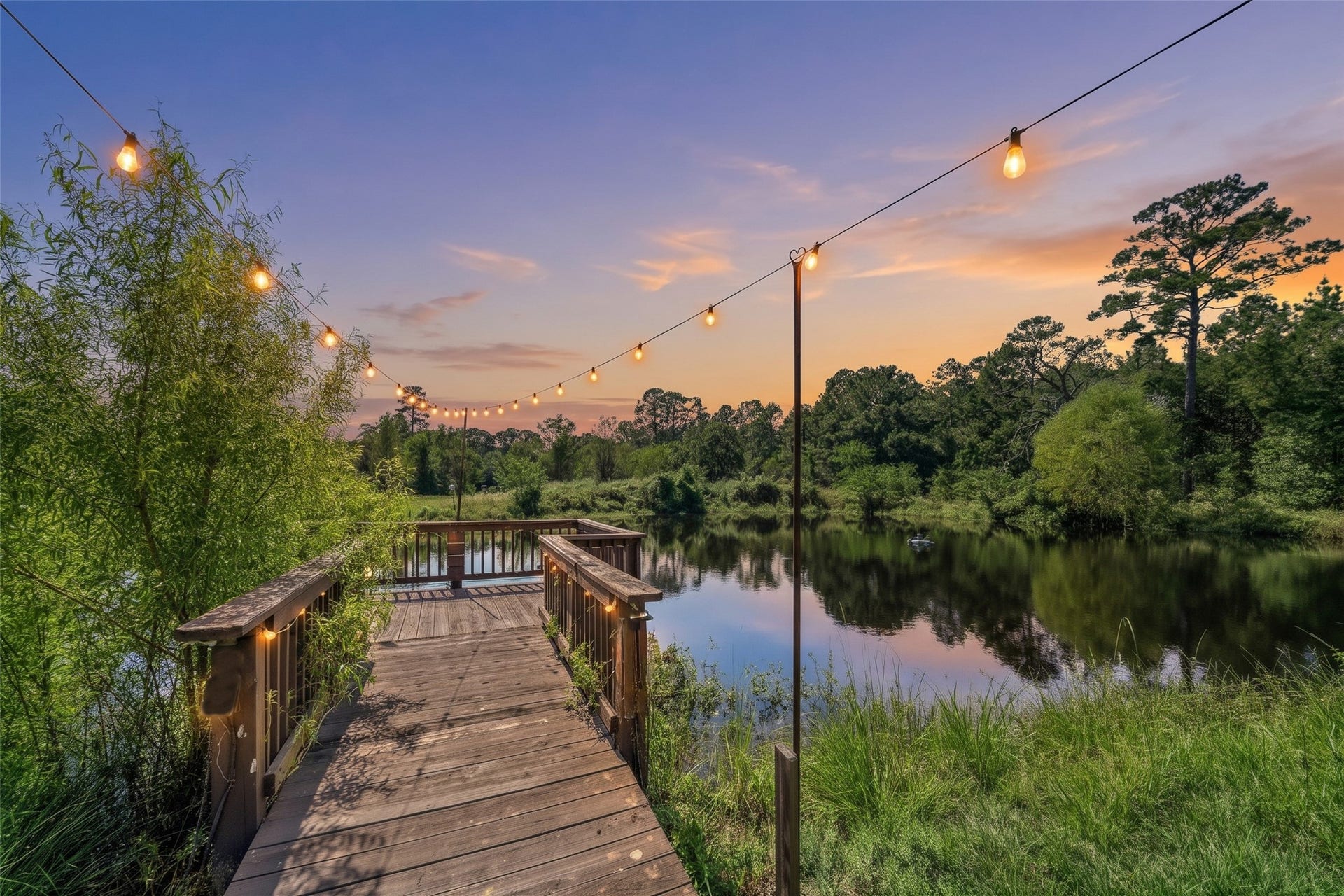 Scenic pond with a wooden dock and overhead string lights creates a picturesque backdrop for wedding photos, special gatherings, and peaceful sunset views.