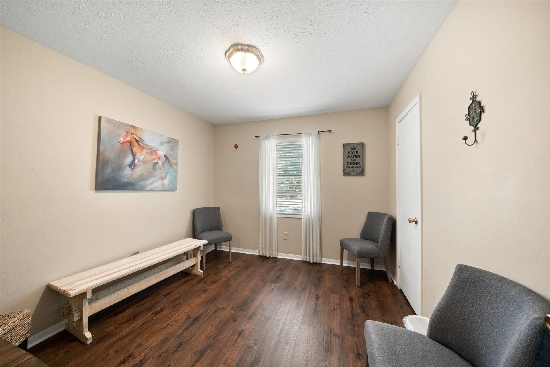 Guest house room featuring wood flooring, neutral walls, and multiple windows providing natural light.