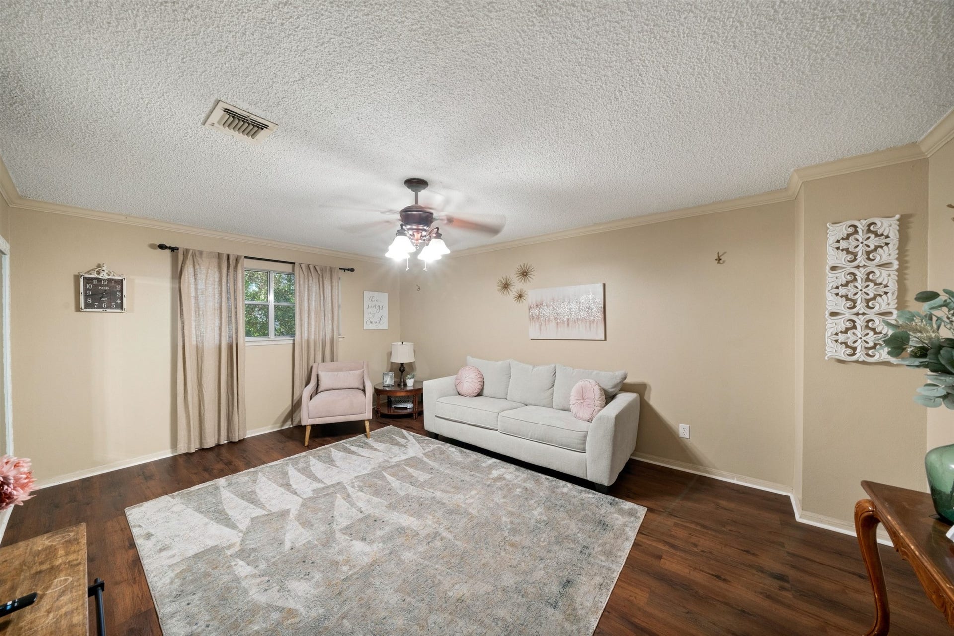 Spacious room with wood flooring, a chandelier, and multiple windows, currently arranged as a lounge with room for varied furniture layouts.