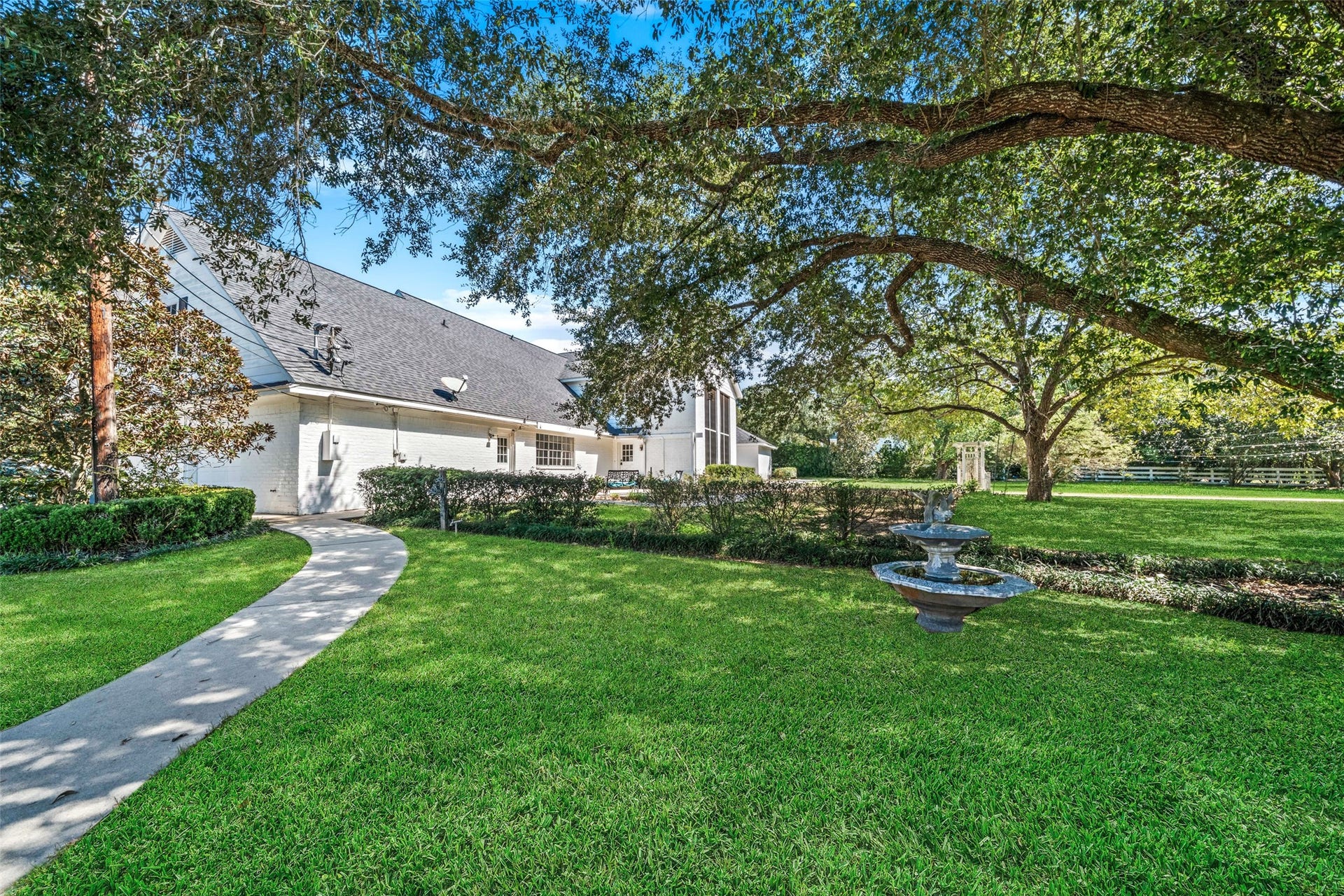 Charming chapel framed by mature shade trees, with a paved walkway and spacious lawn creating a picturesque setting for weddings and special ceremonies.