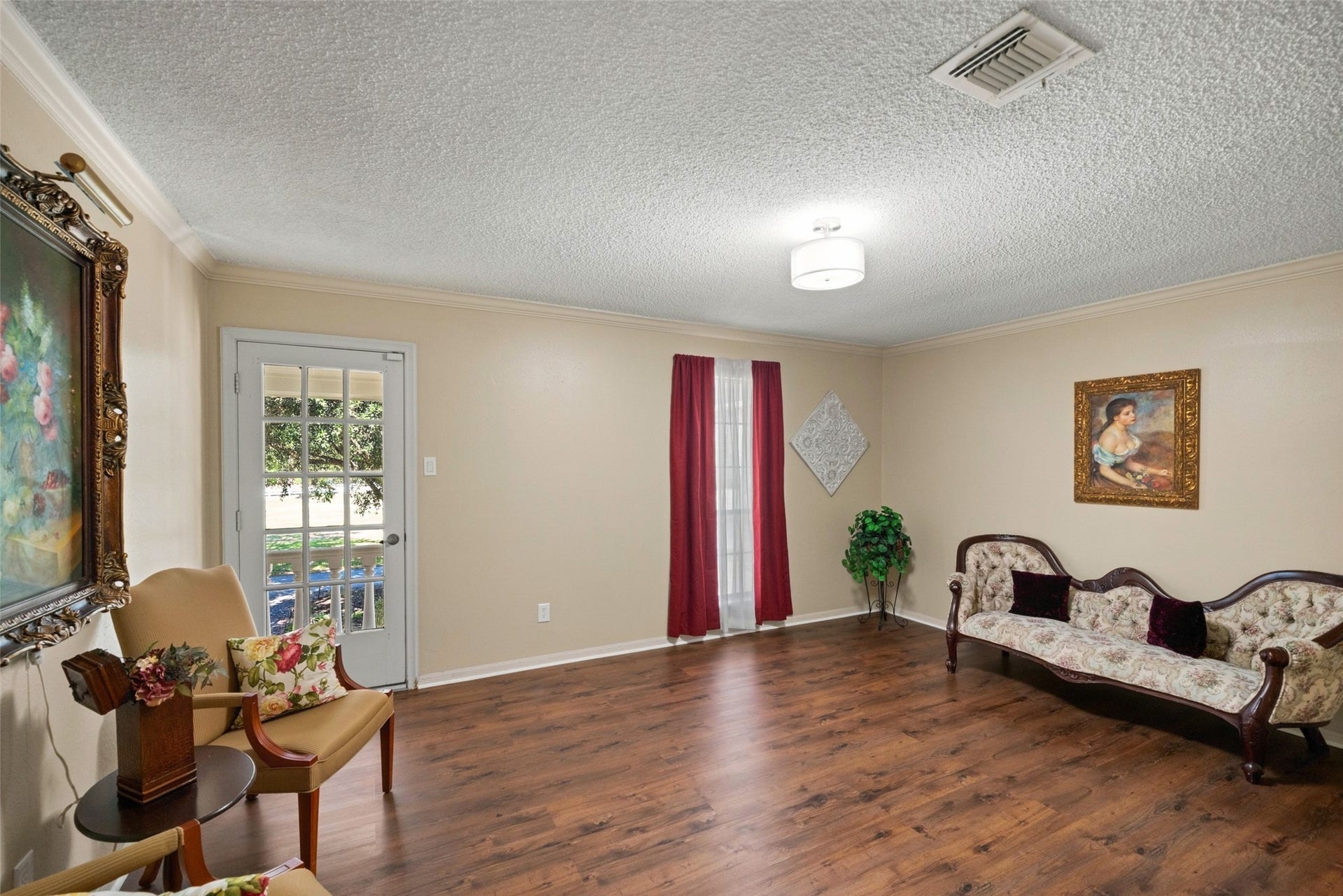 Spacious room overlooking a balcony, currently used as a getting-ready space for the venue, with potential for bedroom use. Features include wood flooring, a chandelier, and natural light.