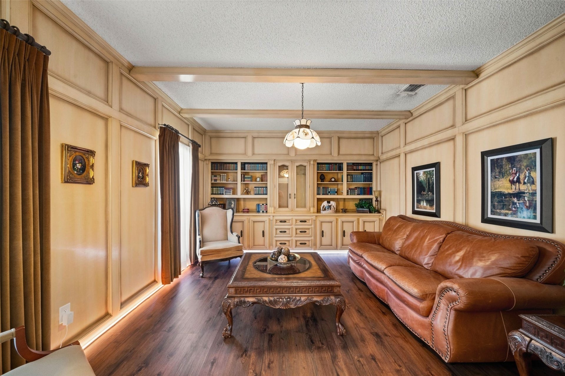 Alternate view of the sitting area showcasing built-in shelving, wood trim, and space for seating beneath exposed ceiling beams.