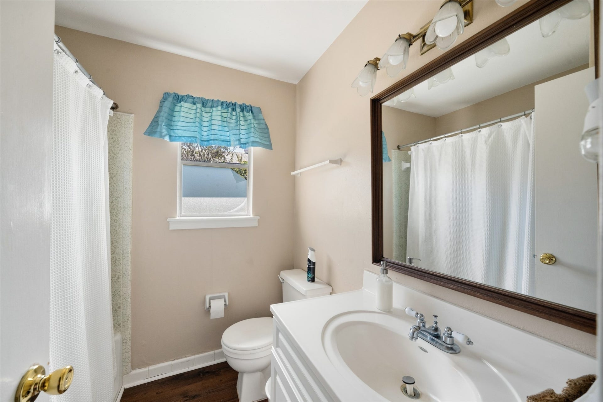 Guest house bathroom featuring a vanity with storage, a large framed mirror, a window, and a tub/shower combination.