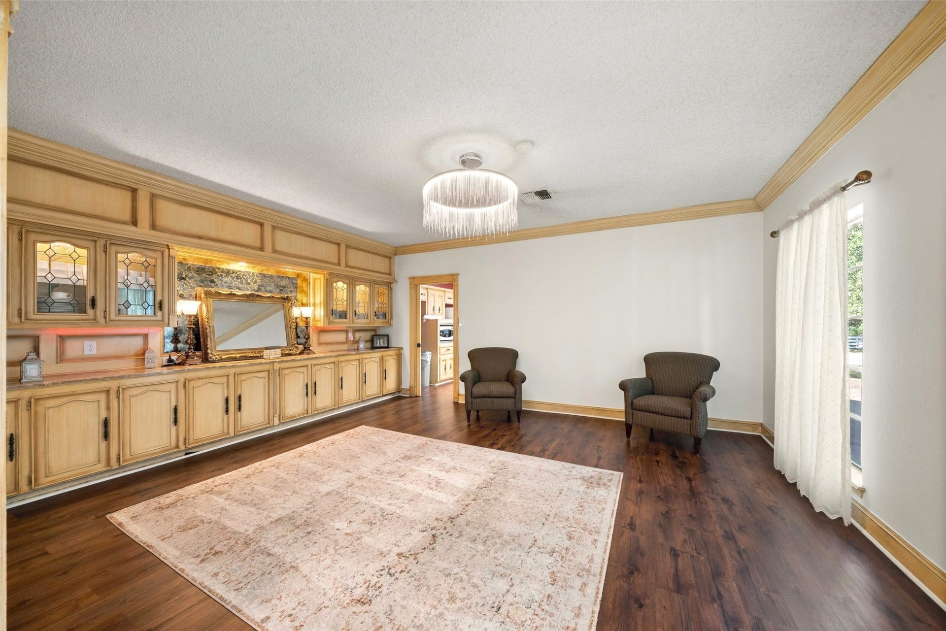 Sitting room featuring extensive built-in cabinetry, glass-front display cabinets, a ceiling fan, and French doors.