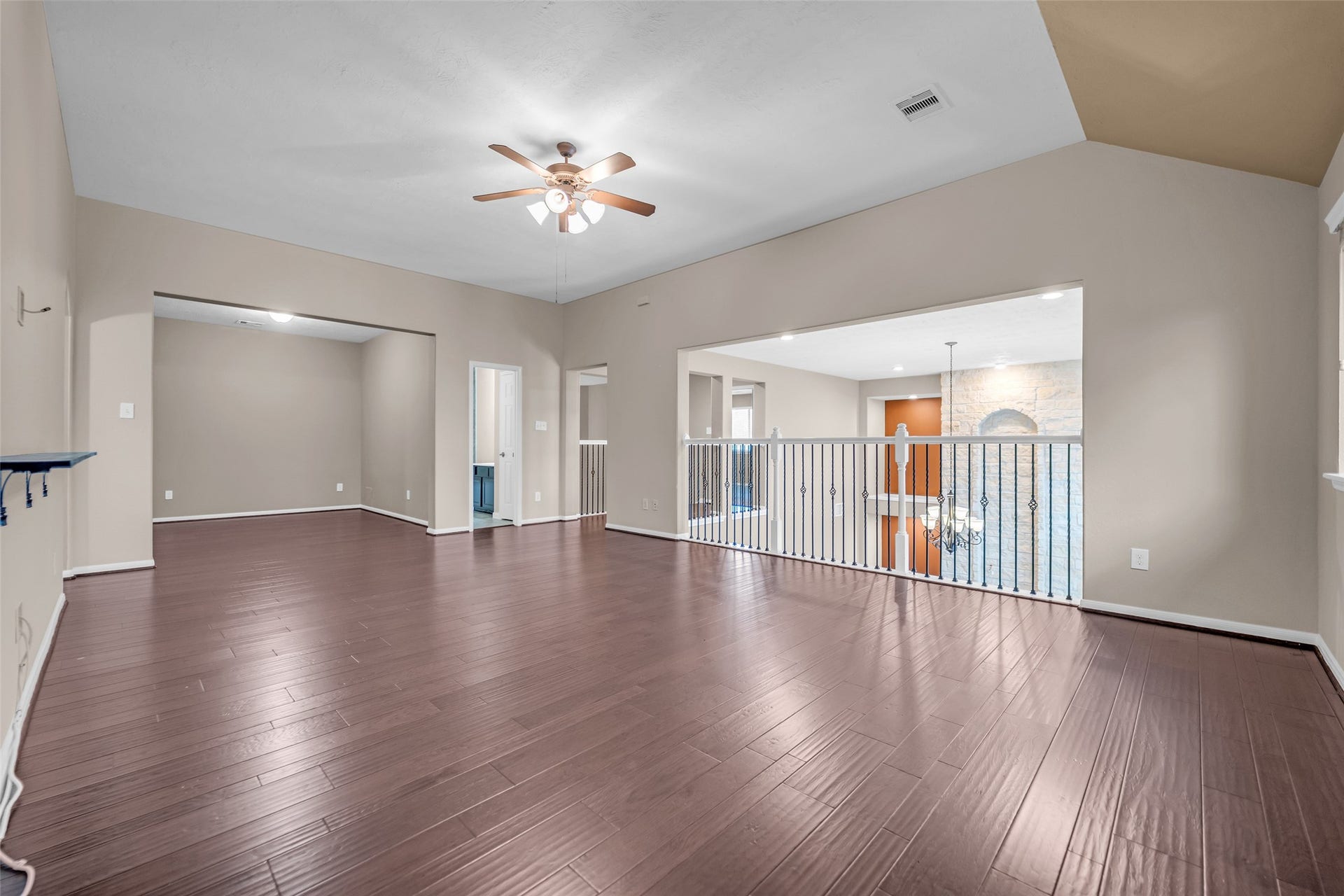 7907 Dunlap Field Lane, Richmond, TX 77407 Open-concept living space featuring rich hardwood floors, a central ceiling fan, and a stylish railing overlooking the lower levelideal for hosting guests or relaxing with family.