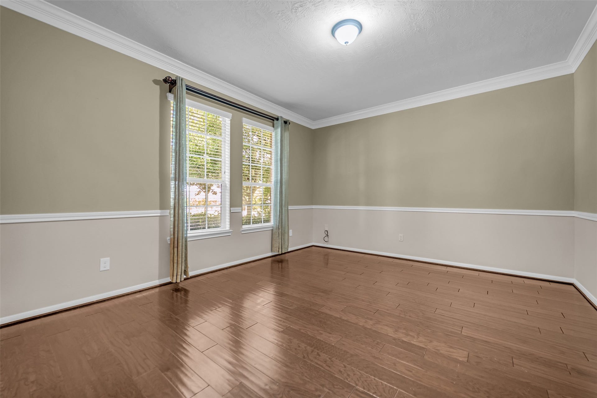 7907 Dunlap Field Lane, Richmond, TX 77407 Bright and spacious room featuring elegant wood flooring, large windows with ample natural light, and tasteful wainscoting for a classic touch.