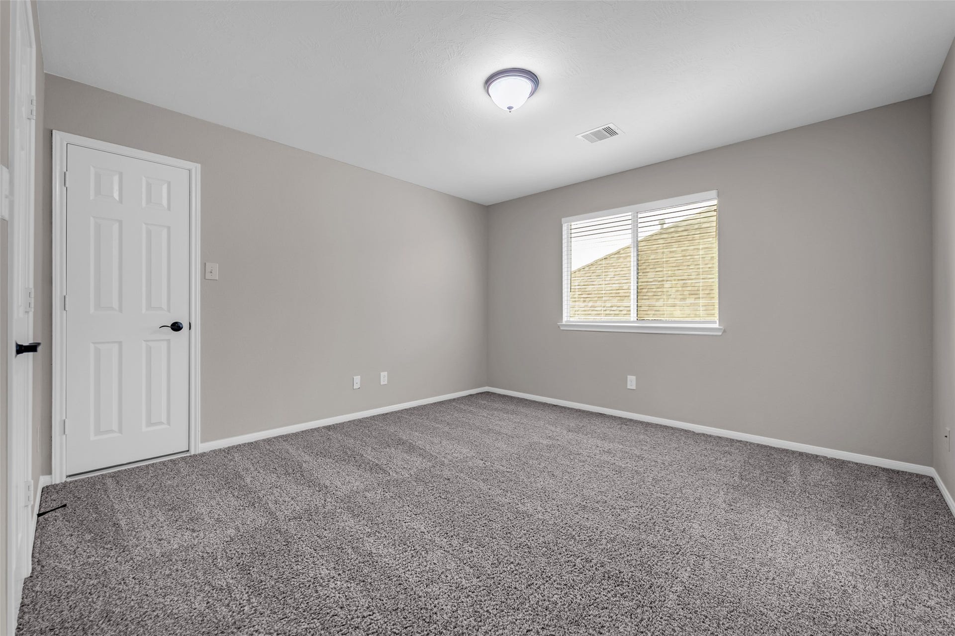 7907 Dunlap Field Lane, Richmond, TX 77407 Inviting secondary bedroom featuring plush, soft gray carpeting, clean neutral walls, and a large sunlit window that fills the space with warm natural light.