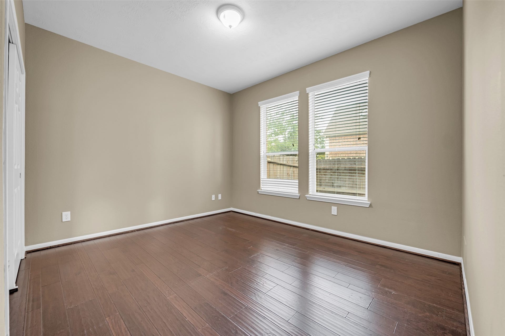 7907 Dunlap Field Lane, Richmond, TX 77407 Bright, open room highlighted by rich hardwood floors and a fresh, neutral color palette, framed by large windows creating a cheerful and inviting ambiance.