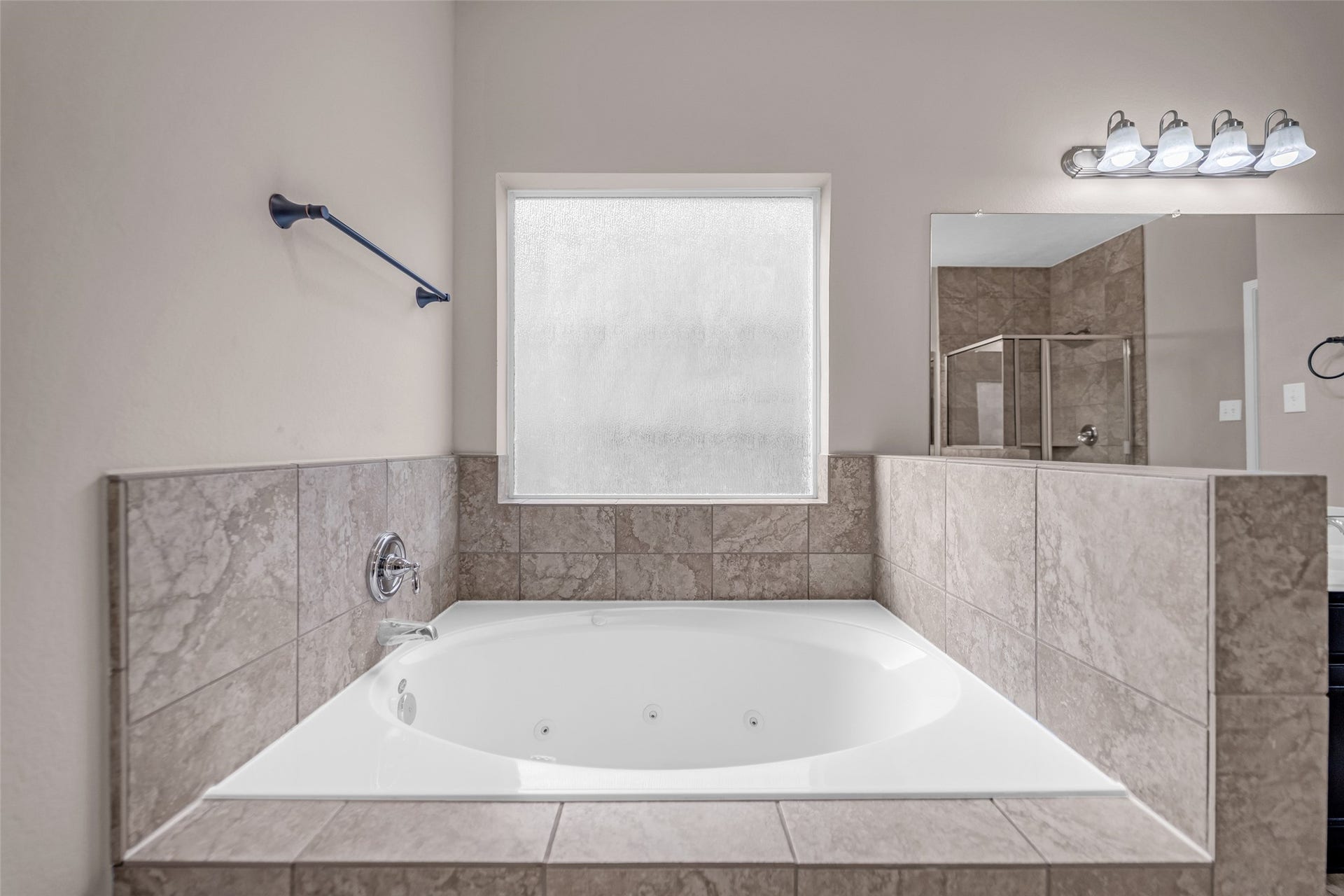 7907 Dunlap Field Lane, Richmond, TX 77407 Elegant ensuite bath highlighting a spacious jetted soaking tub, beautifully detailed tile surround, and a separate modern glass shower stall.