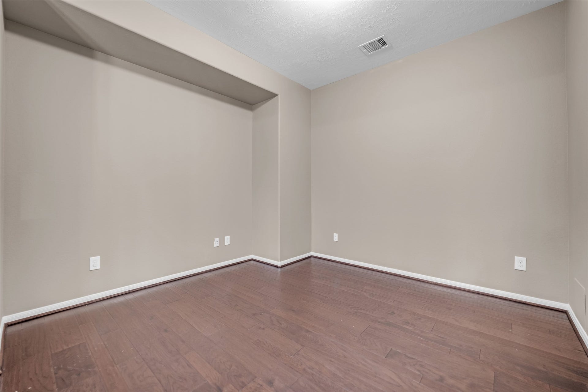 7907 Dunlap Field Lane, Richmond, TX 77407 Light-filled room highlighted by warm wood floors, soft neutral tones, and a recessed display nook ready for custom organization or artwork.