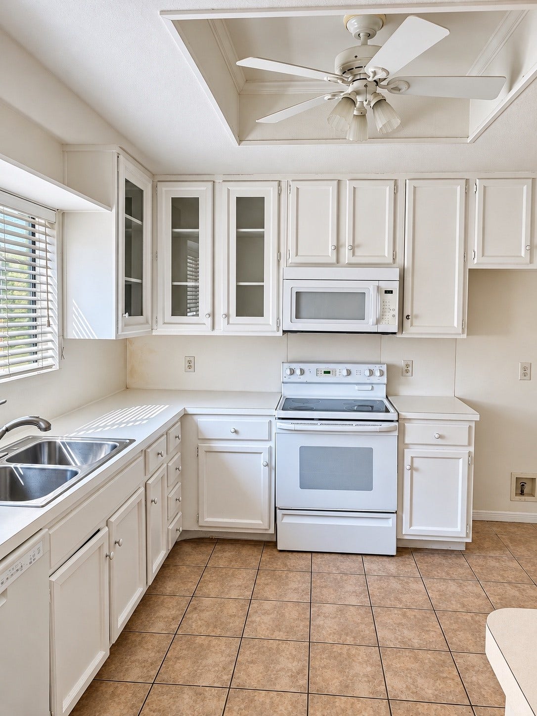 11711 Memorial Drive, #313, Houston, TX 77024 Light filled kitchen with white cabinetry, glass front accents, ample counter space and tile flooring.