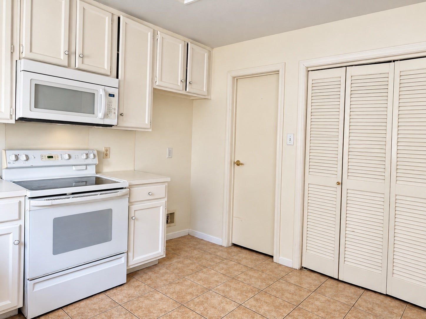 11711 Memorial Drive, #313, Houston, TX 77024 Charming kitchen with white cabinetry, an electric range, built-in-microwave, easy care tile fooring, with access to spacious pantry, easy access utility room