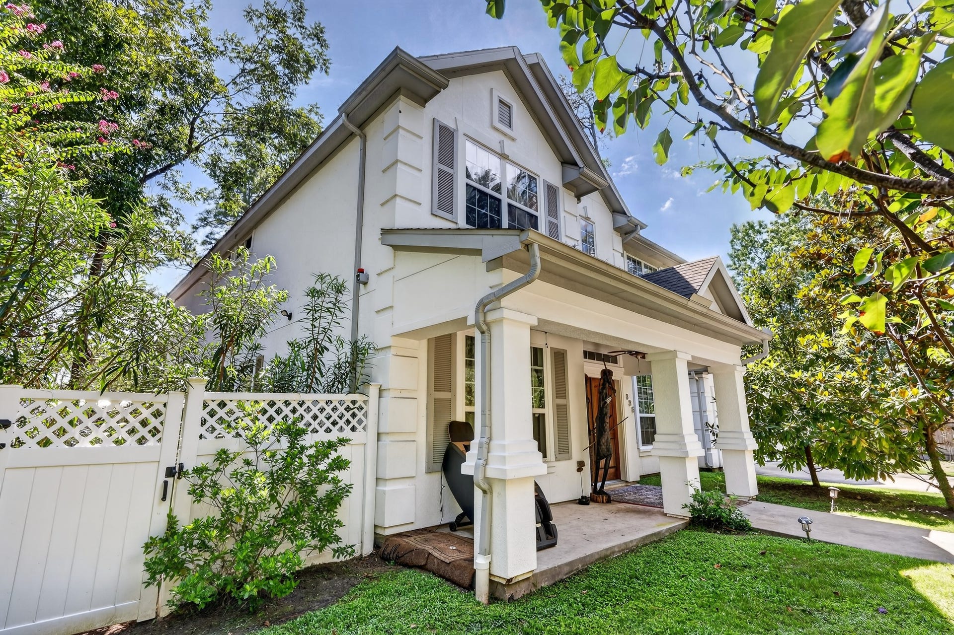 Charming covered front porch framed by lush greenery.
