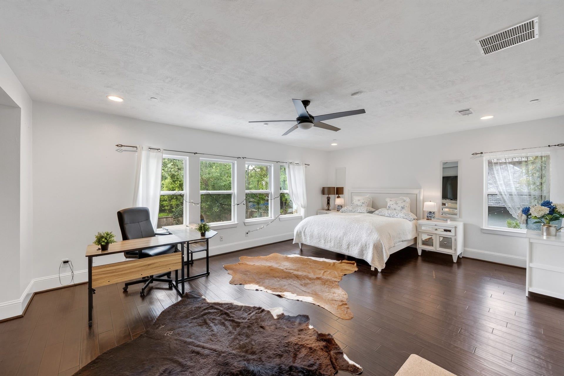 Upstairs primary bedroom featuring a wall of windows and pool view.
