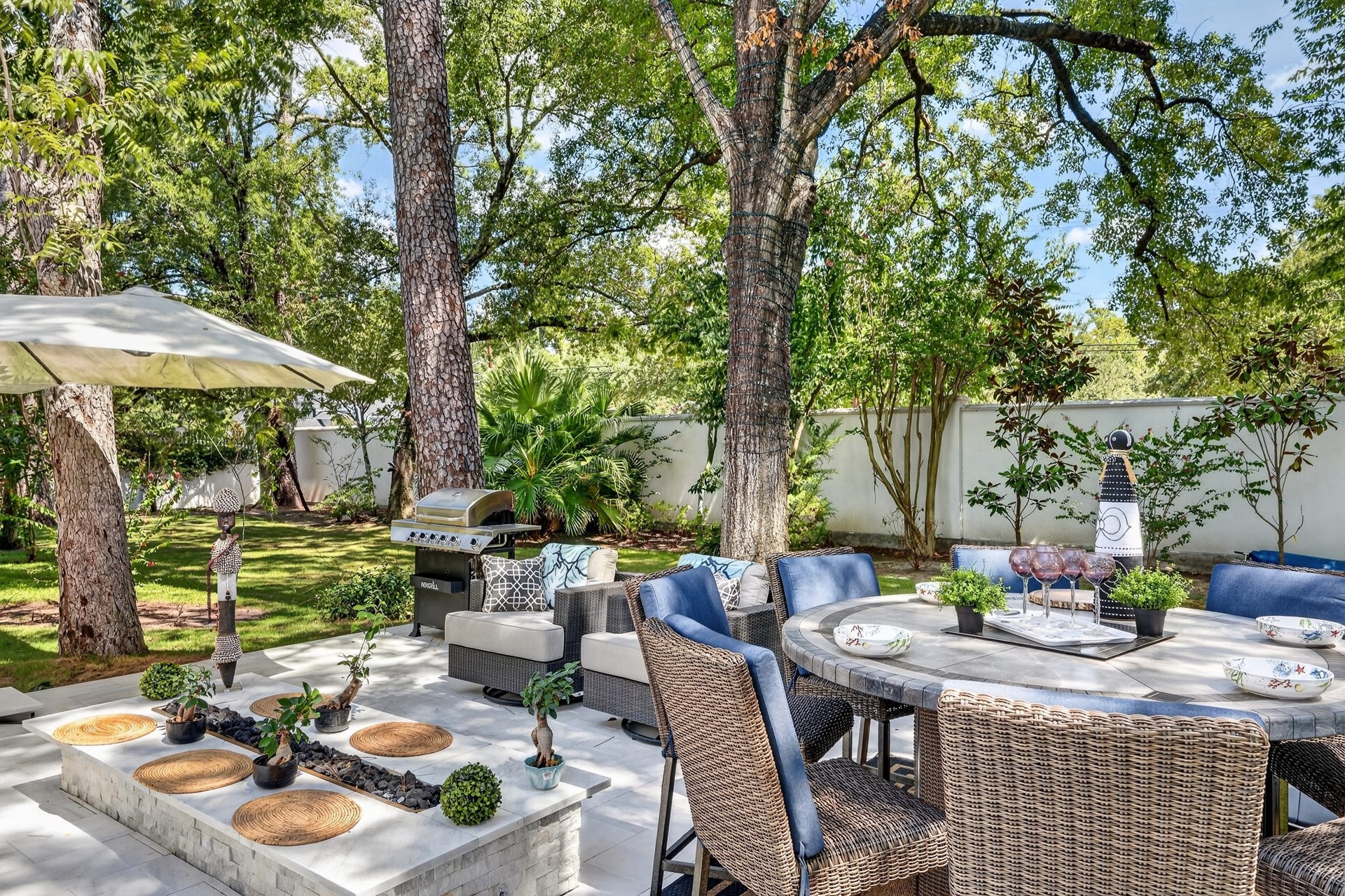 Elegant outdoor living area surrounded by mature trees and lush landscaping.