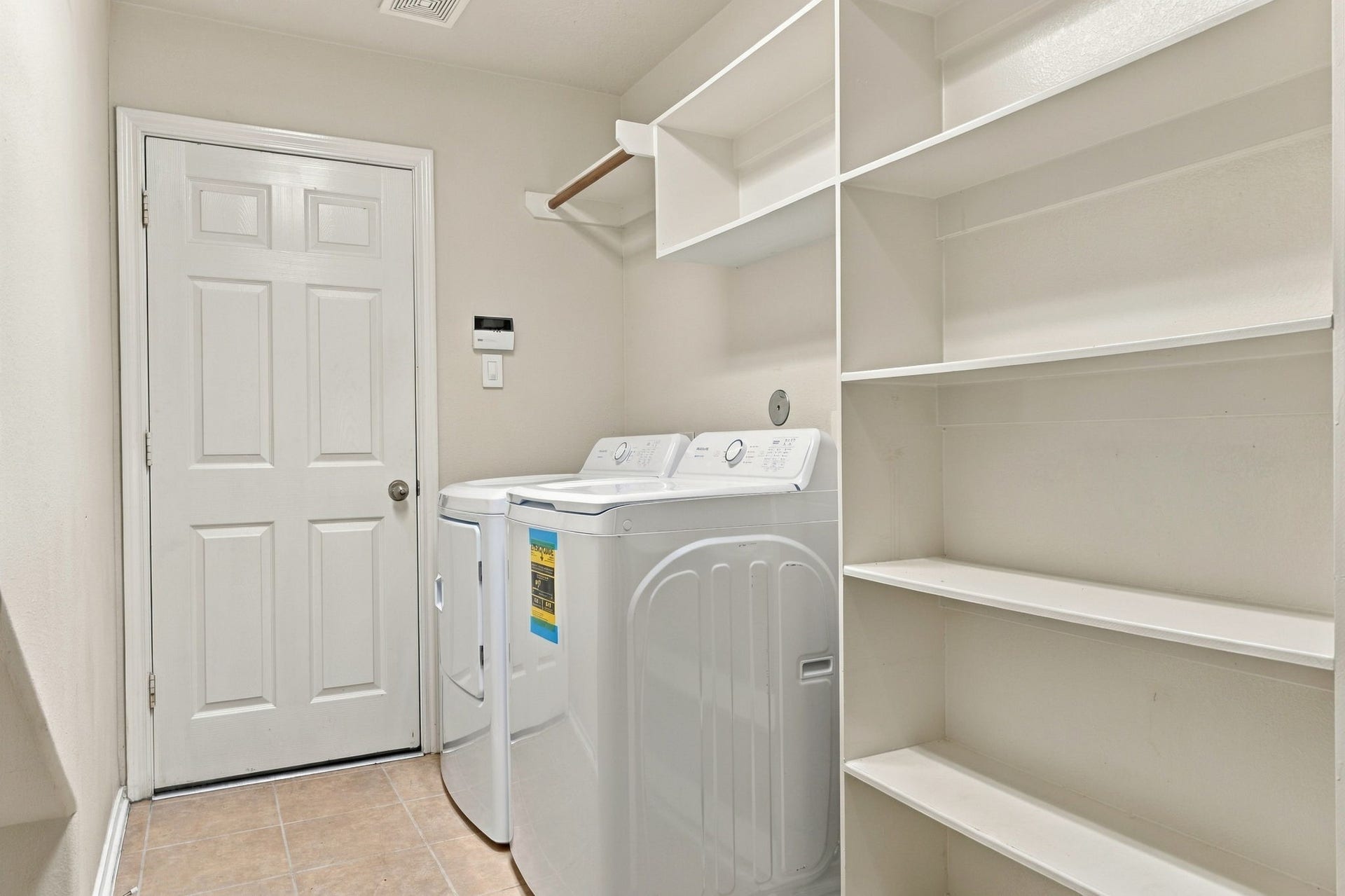 Spacious laundry room featuring modern appliances, ample shelving, and convenient storage options.