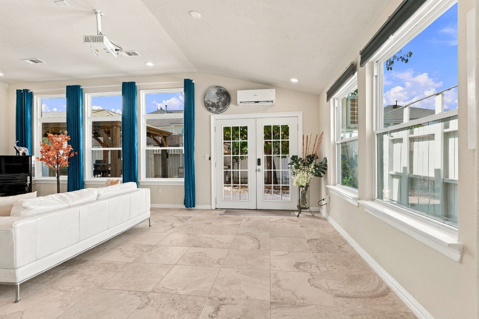 Bright and inviting living space with large windows, natural light, and elegant tile flooring, perfect for relaxation and entertaining.