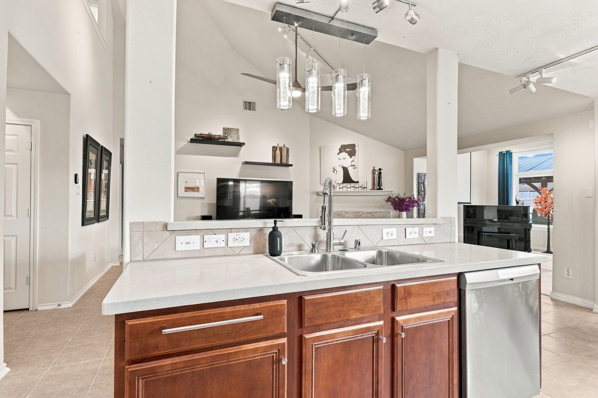 Modern kitchen with elegant pendant lighting, sleek stainless steel appliances, and a dual sink, offering a spacious and inviting open layout.