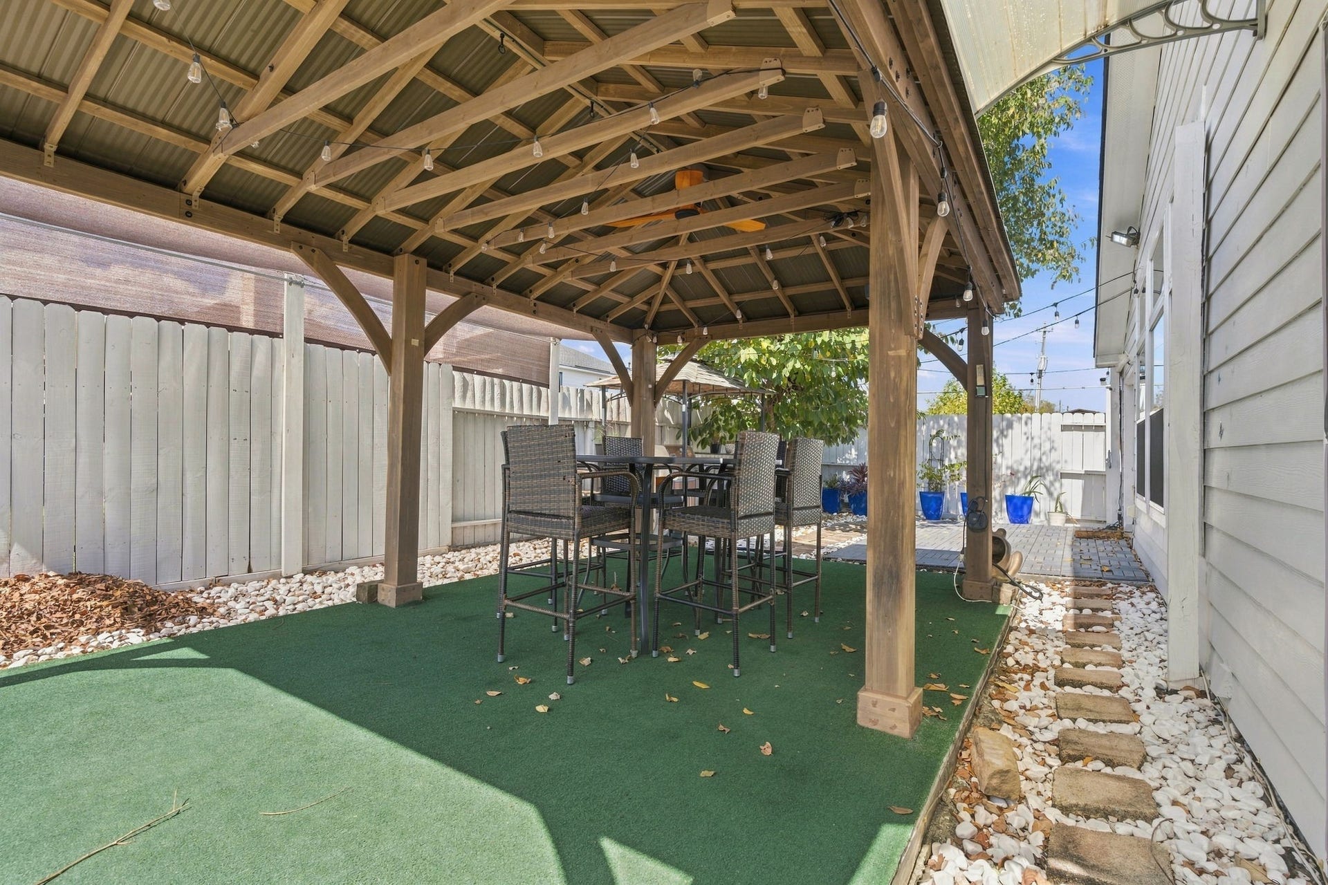 Charming backyard retreat featuring a wooden pergola with a cozy dining set, perfect for outdoor entertaining.