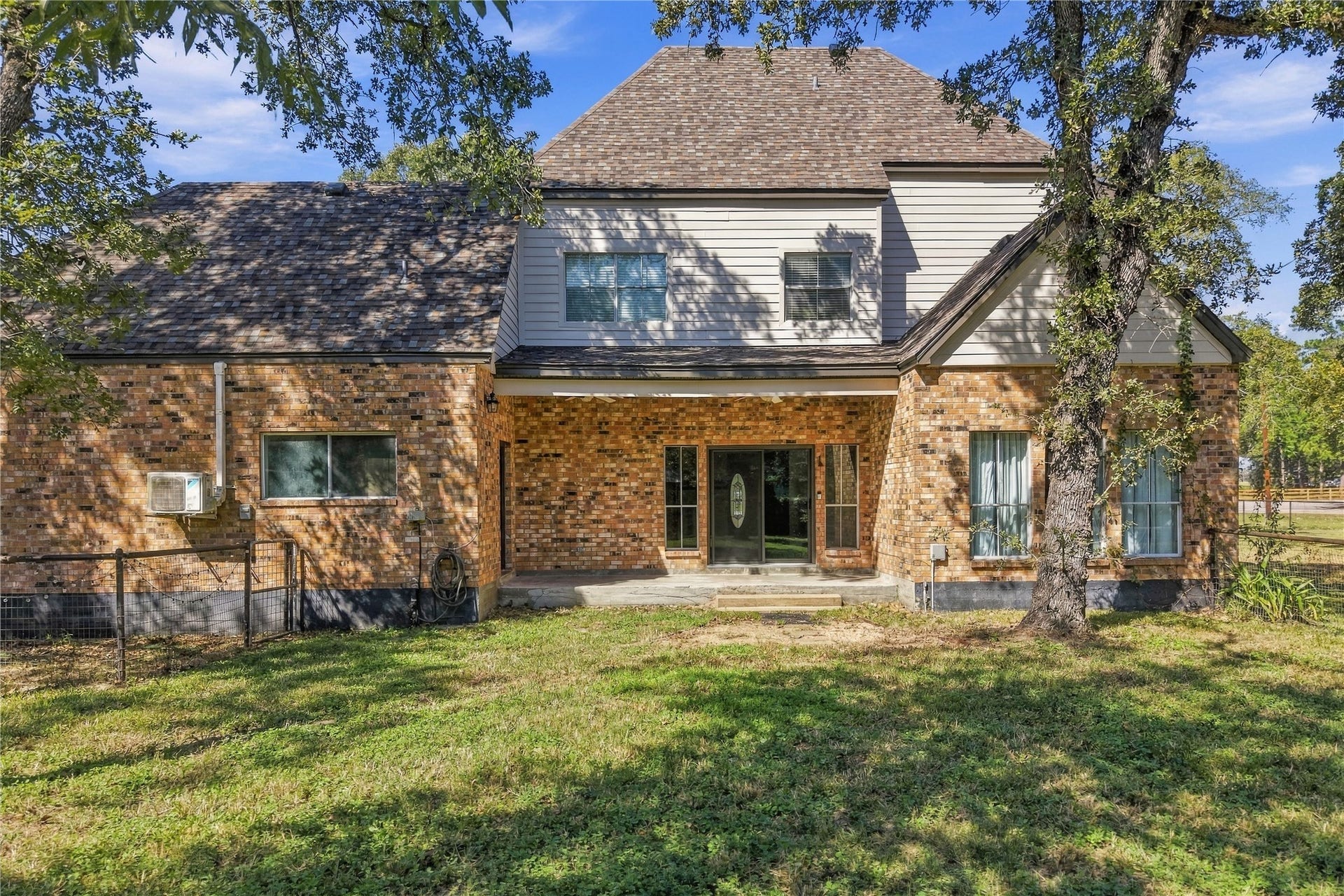 24904 Robin Hood Lane, Hockley, TX 77447 Rear exterior featuring a covered patio, brick exterior, and views of the tree-shaded backyard.