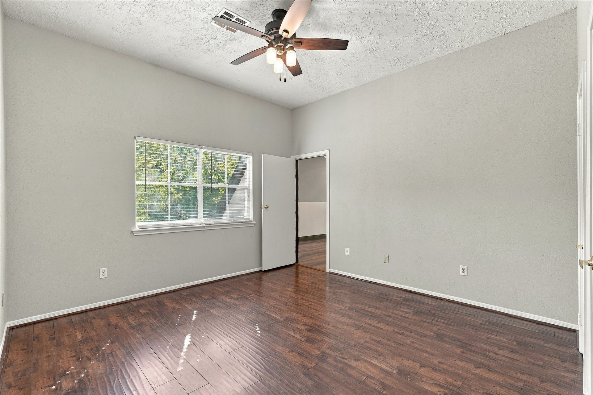 24904 Robin Hood Lane, Hockley, TX 77447 Upstairs secondary bedroom with wood flooring, ceiling fan, and a large window offering views of the mature trees.