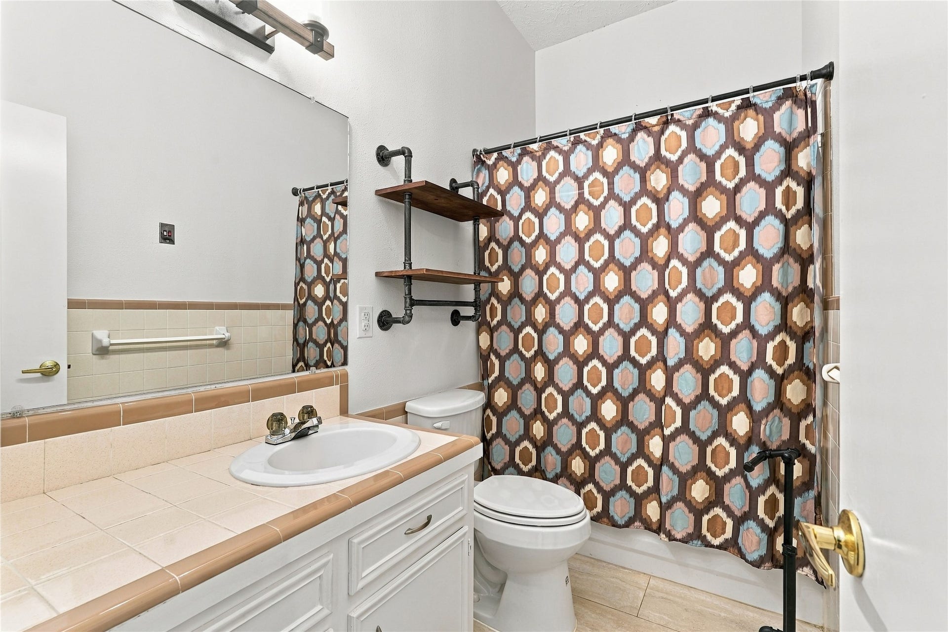 24904 Robin Hood Lane, Hockley, TX 77447 Upstairs secondary bathroom featuring a tub/shower combination, tile countertop, vanity storage, and additional wall shelving.