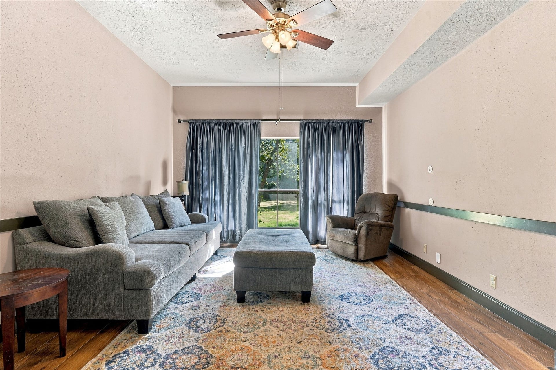 24904 Robin Hood Lane, Hockley, TX 77447 Comfortable family room featuring wood-look flooring, ceiling fan, and large window overlooking the yard.