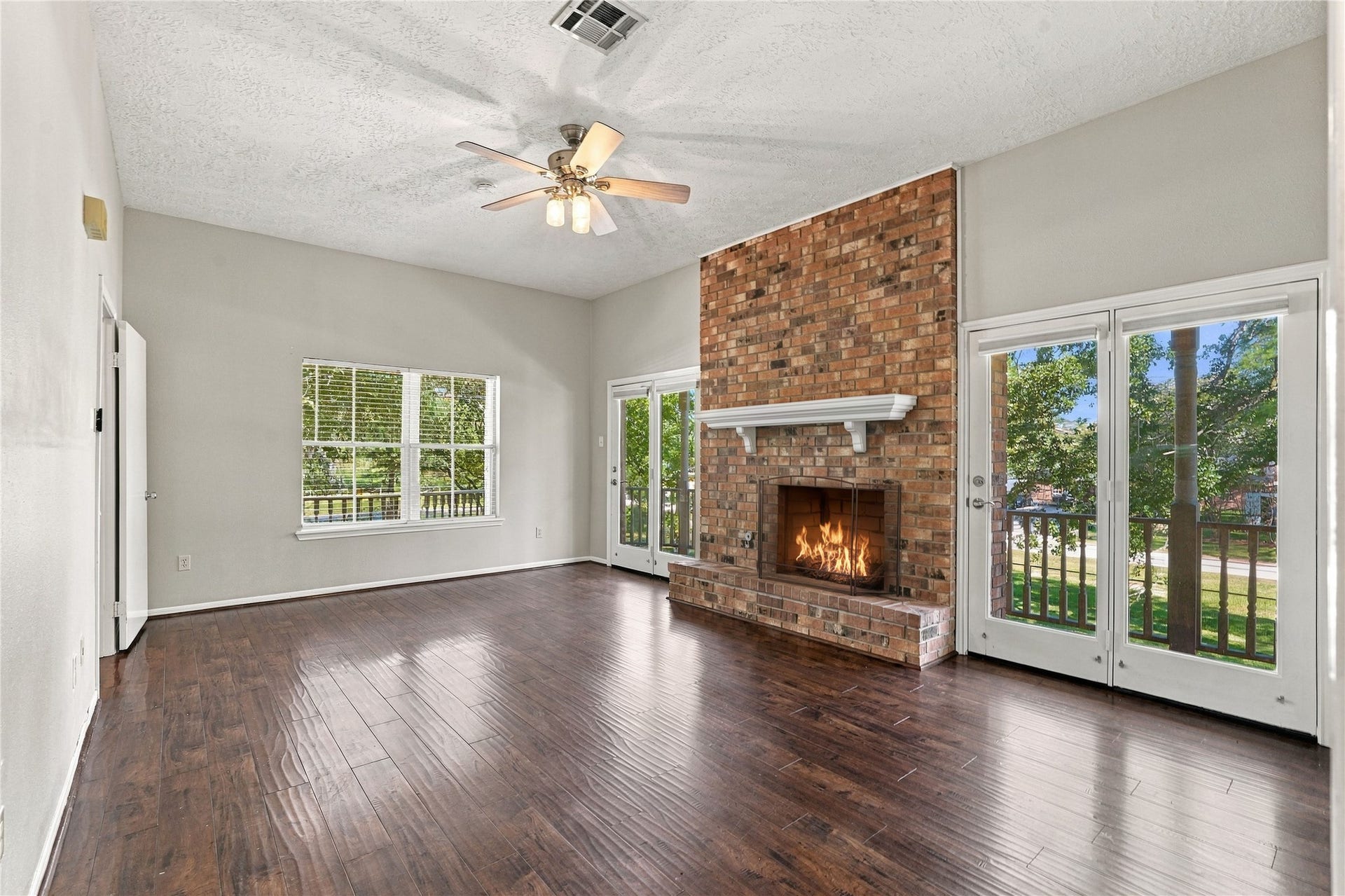 24904 Robin Hood Lane, Hockley, TX 77447 Additional view of the primary bedroom highlighting the brick fireplace, generous floor space, and multiple windows and French doors overlooking the property.
