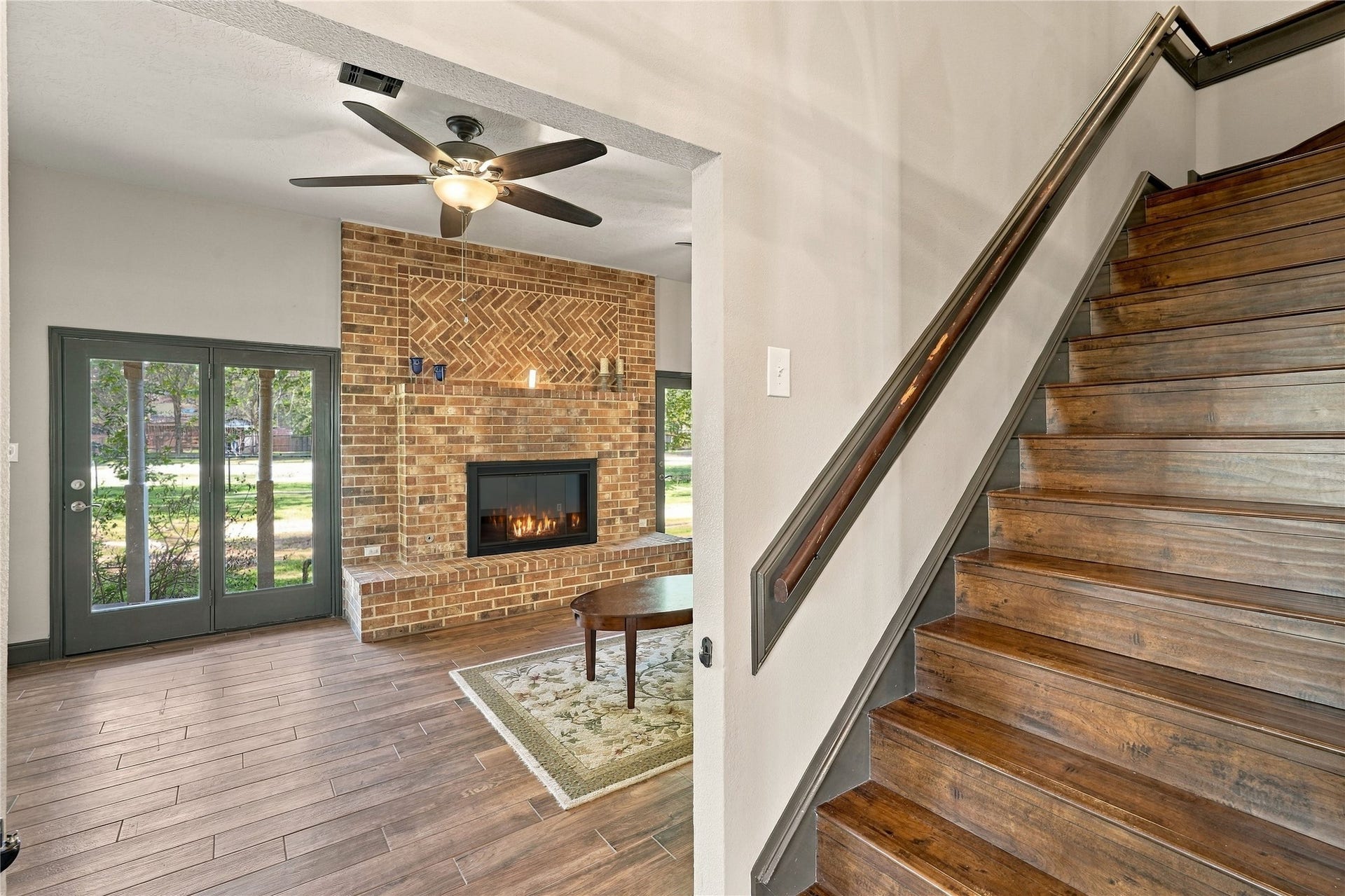 24904 Robin Hood Lane, Hockley, TX 77447 View from the entry showcasing the living room's floor-to-ceiling brick fireplace, wood-look flooring, and staircase.