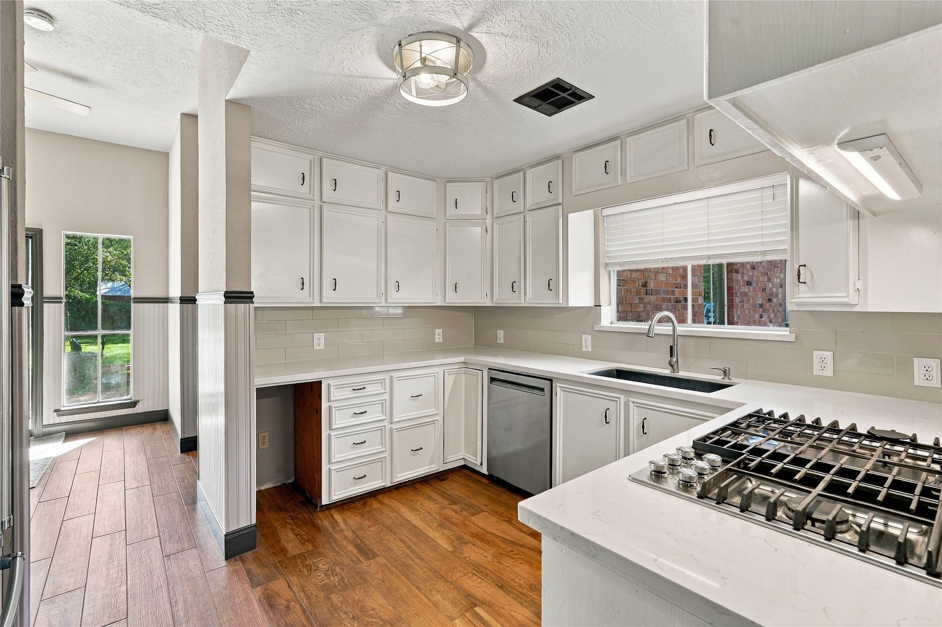 24904 Robin Hood Lane, Hockley, TX 77447 Bright kitchen featuring white cabinetry, quartz countertops, subway tile backsplash, stainless steel appliances, and wood flooring.