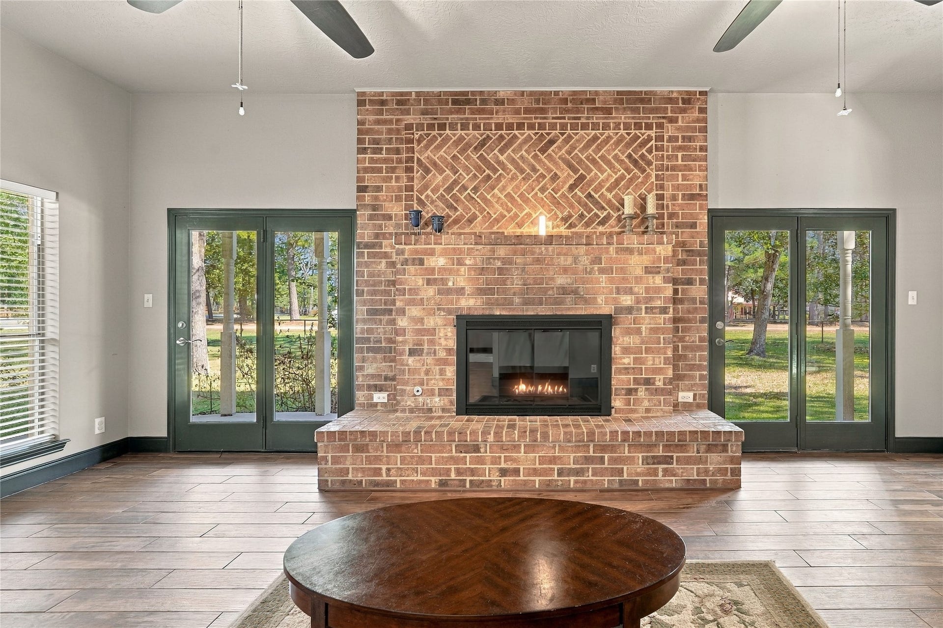 24904 Robin Hood Lane, Hockley, TX 77447 Floor-to-ceiling brick fireplace serves as the focal point of the living room, flanked by glass doors offering natural light and outdoor access.