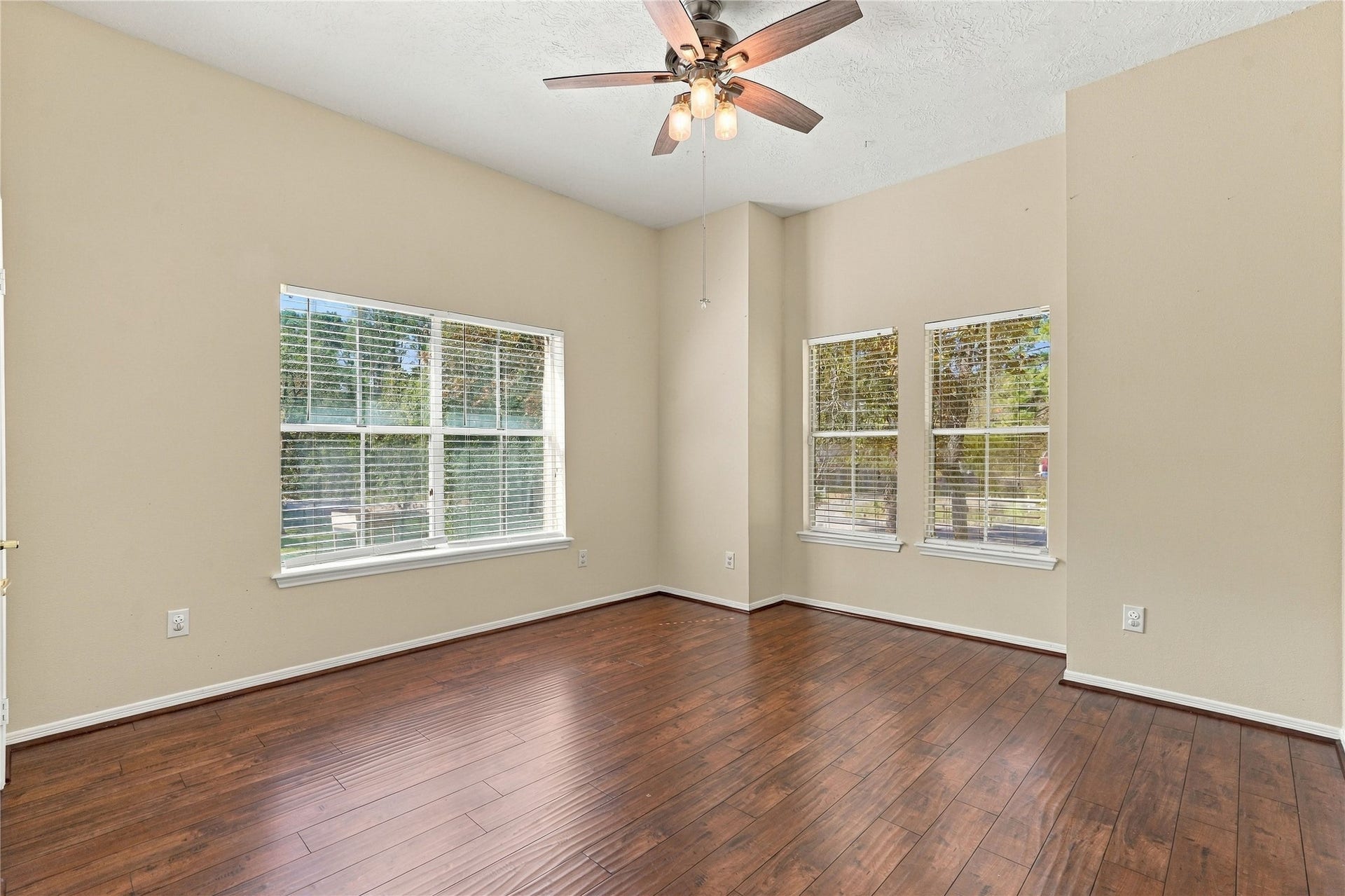 24904 Robin Hood Lane, Hockley, TX 77447 Spacious upstairs secondary bedroom with wood flooring, high ceiling, ceiling fan, and multiple windows overlooking the property.