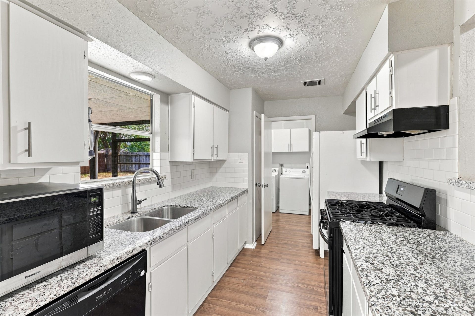 3011 Helmsley Drive, Pearland, TX 77584 Kitchen features granite countertops, white cabinetry, and a window above the sink for natural light.
