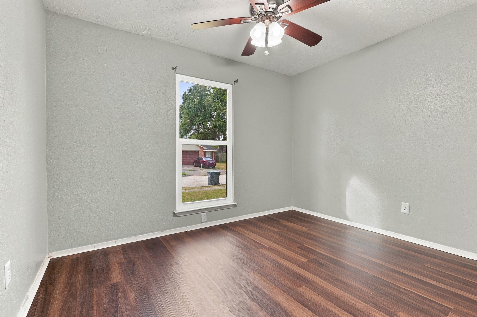 3011 Helmsley Drive, Pearland, TX 77584 Second bedroom offers a ceiling fan, wood-look flooring, and a window overlooking the outdoors.