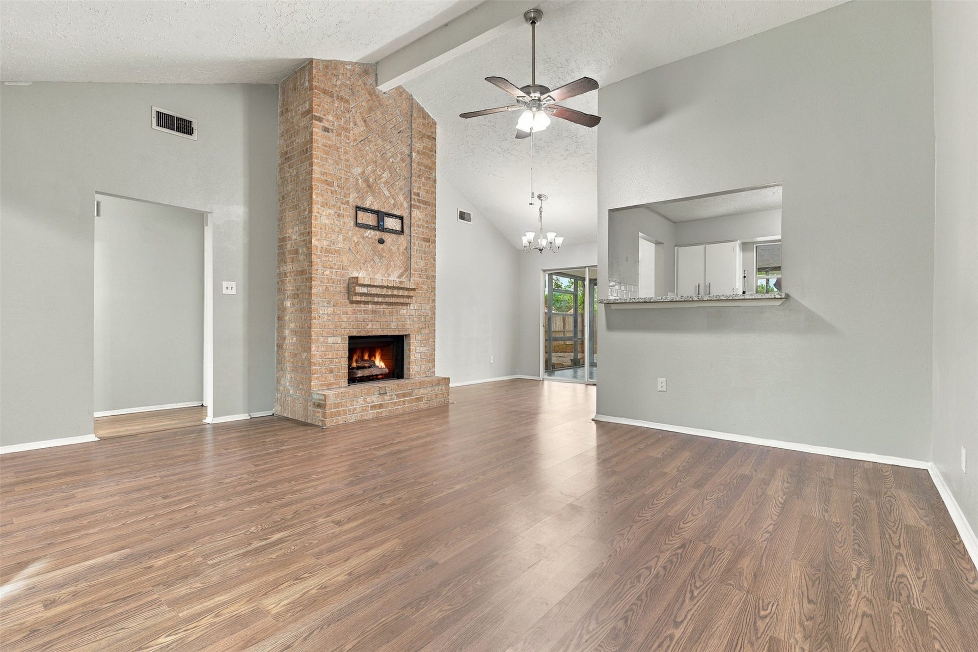 3011 Helmsley Drive, Pearland, TX 77584 A floor-to-ceiling brick gas fireplace anchors the living room, while the kitchen pass-through keeps the spaces connected.