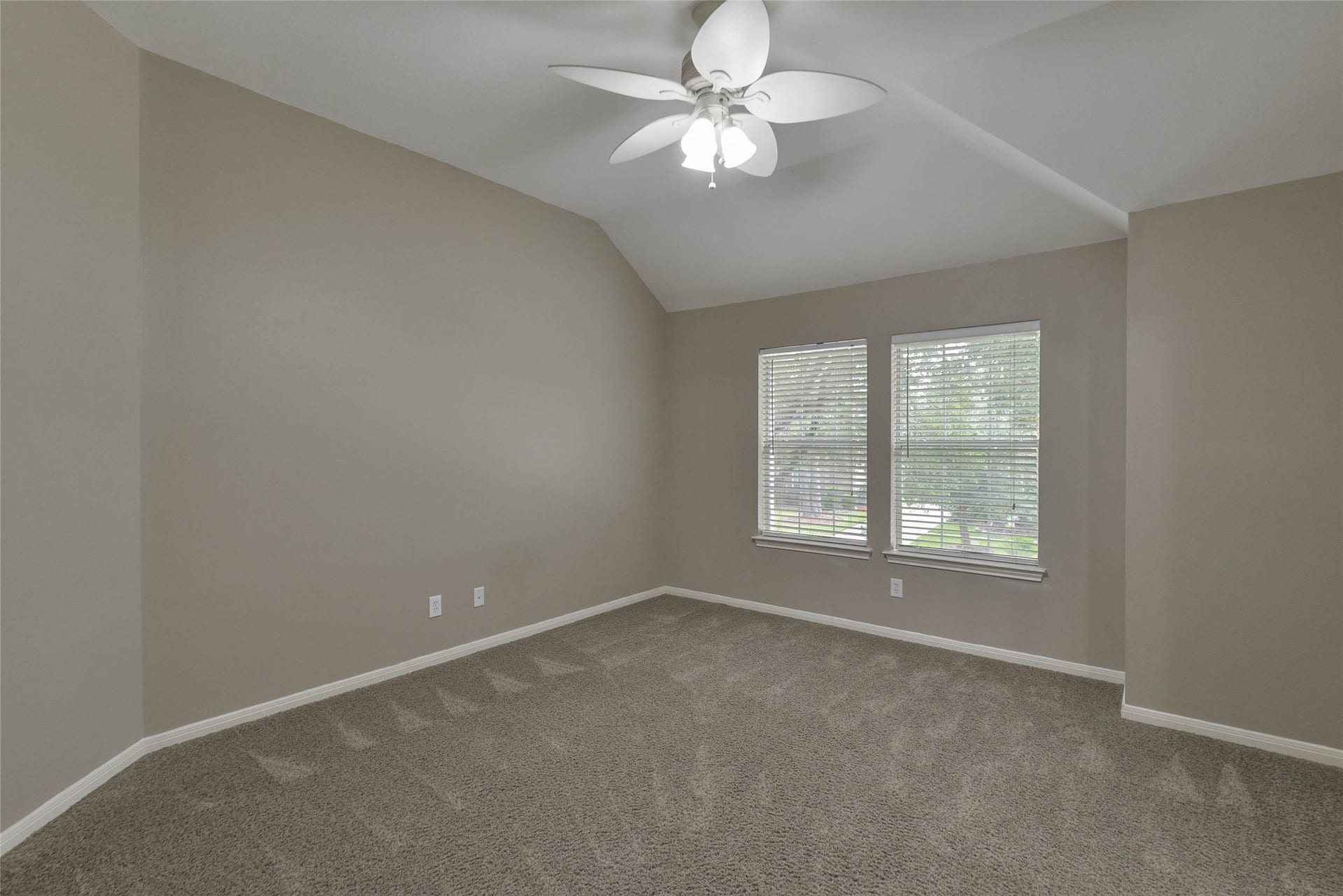 7023 Timber Edge Lane Lane, Humble, TX 77346 Secondary bedroom with plush carpeting, neutral walls, and abundant natural light from two large windows, complete with a stylish ceiling fan.