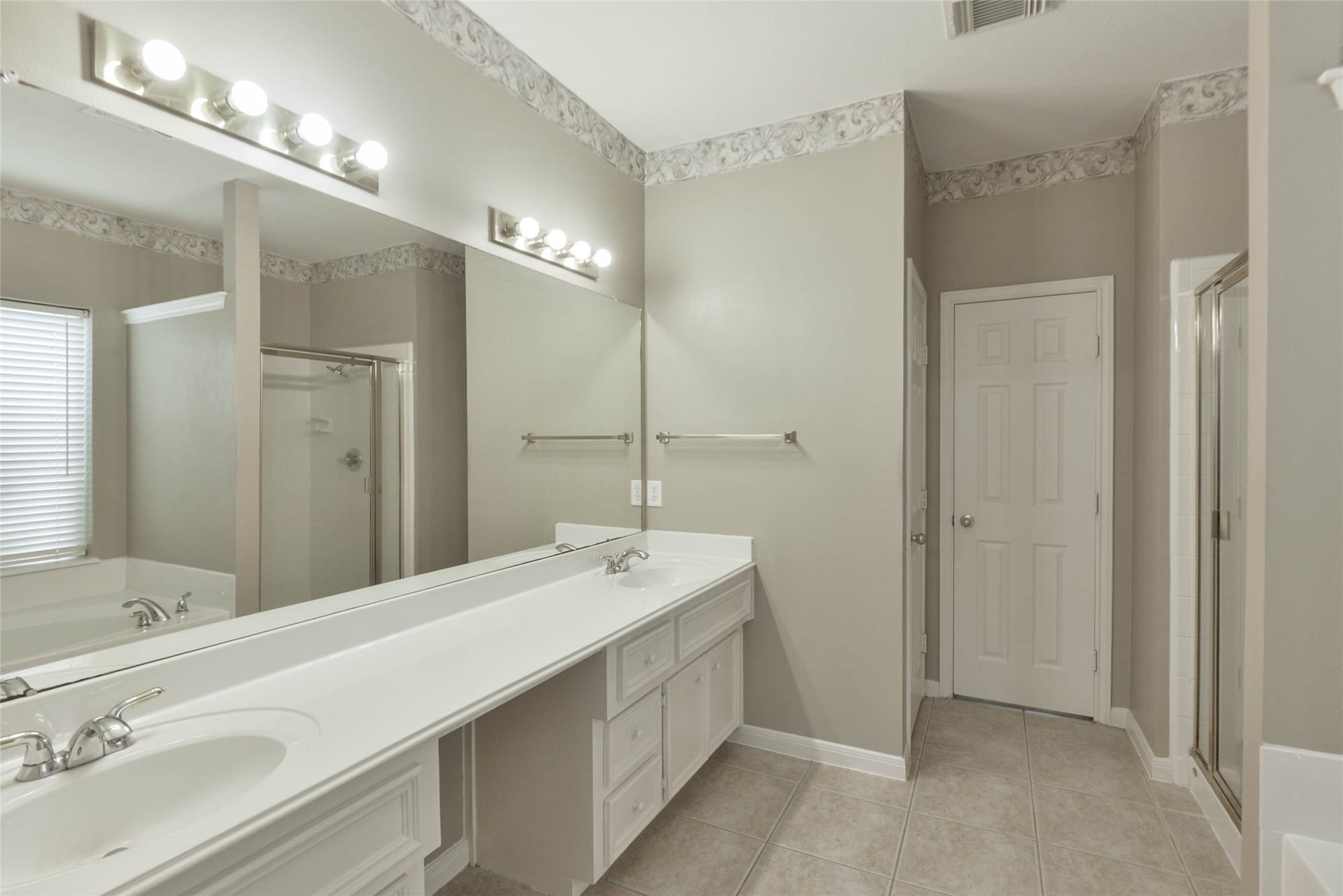 7023 Timber Edge Lane Lane, Humble, TX 77346 Primary bathroom featuring a large double vanity, sleek lighting, and a walk-in shower, all complemented by neutral tones and tile flooring.