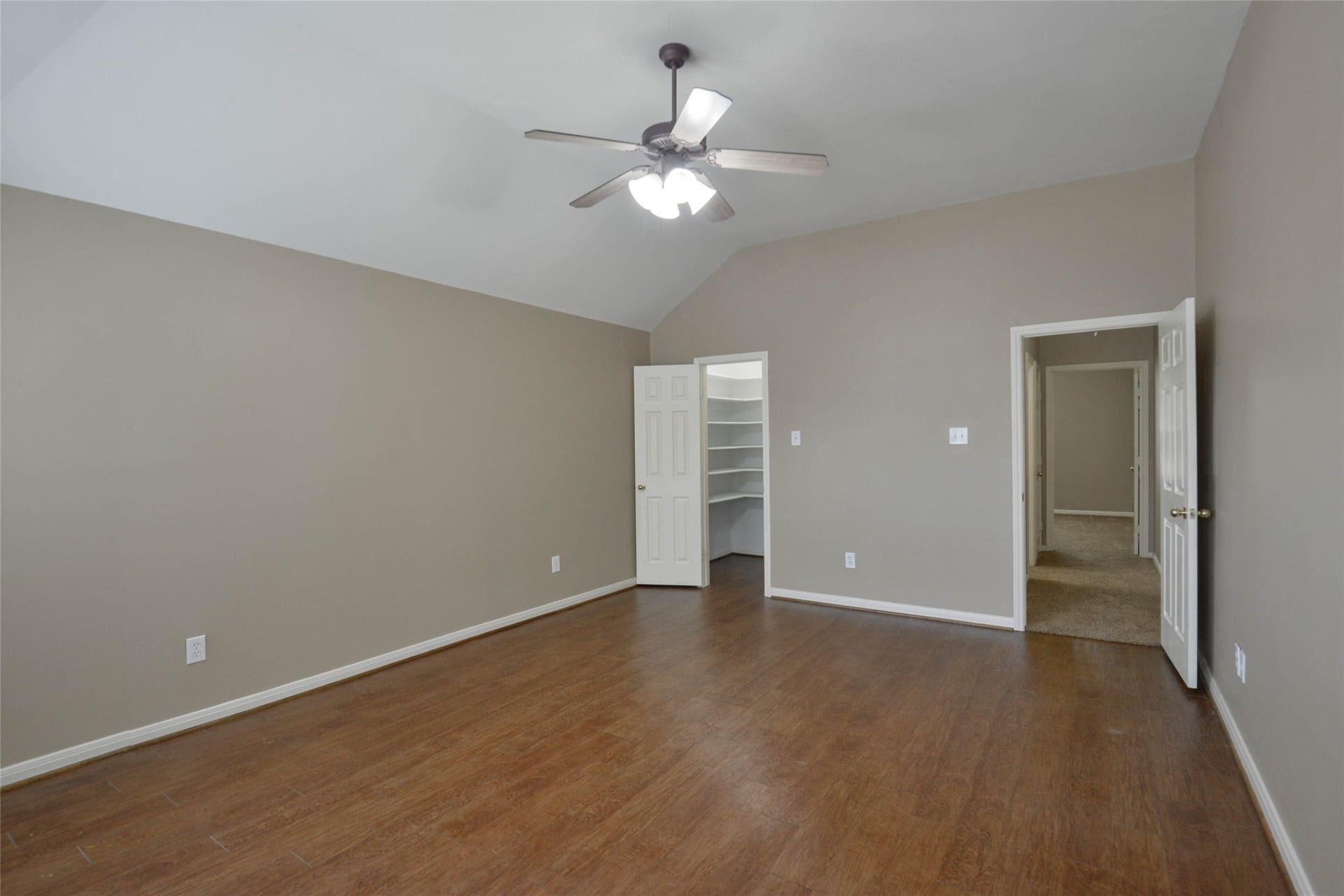7023 Timber Edge Lane Lane, Humble, TX 77346 Secondary bedroom with elegant hardwood floors, neutral walls, and a ceiling fan, featuring a walk-in closet and easy access to an adjacent carpeted area.