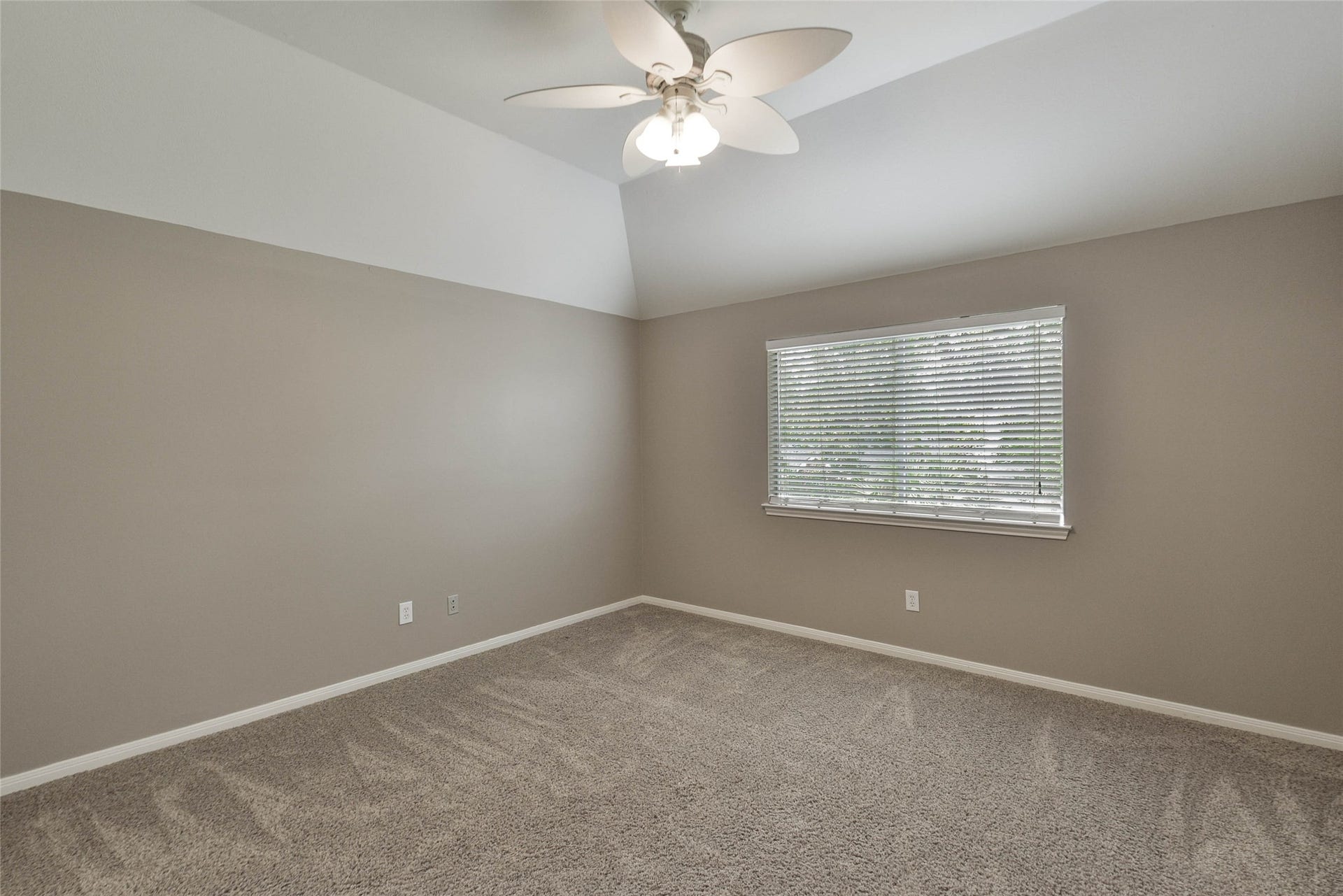 7023 Timber Edge Lane Lane, Humble, TX 77346 Bright secondary bedroom with neutral tones, featuring a ceiling fan and a large window for ample natural light.