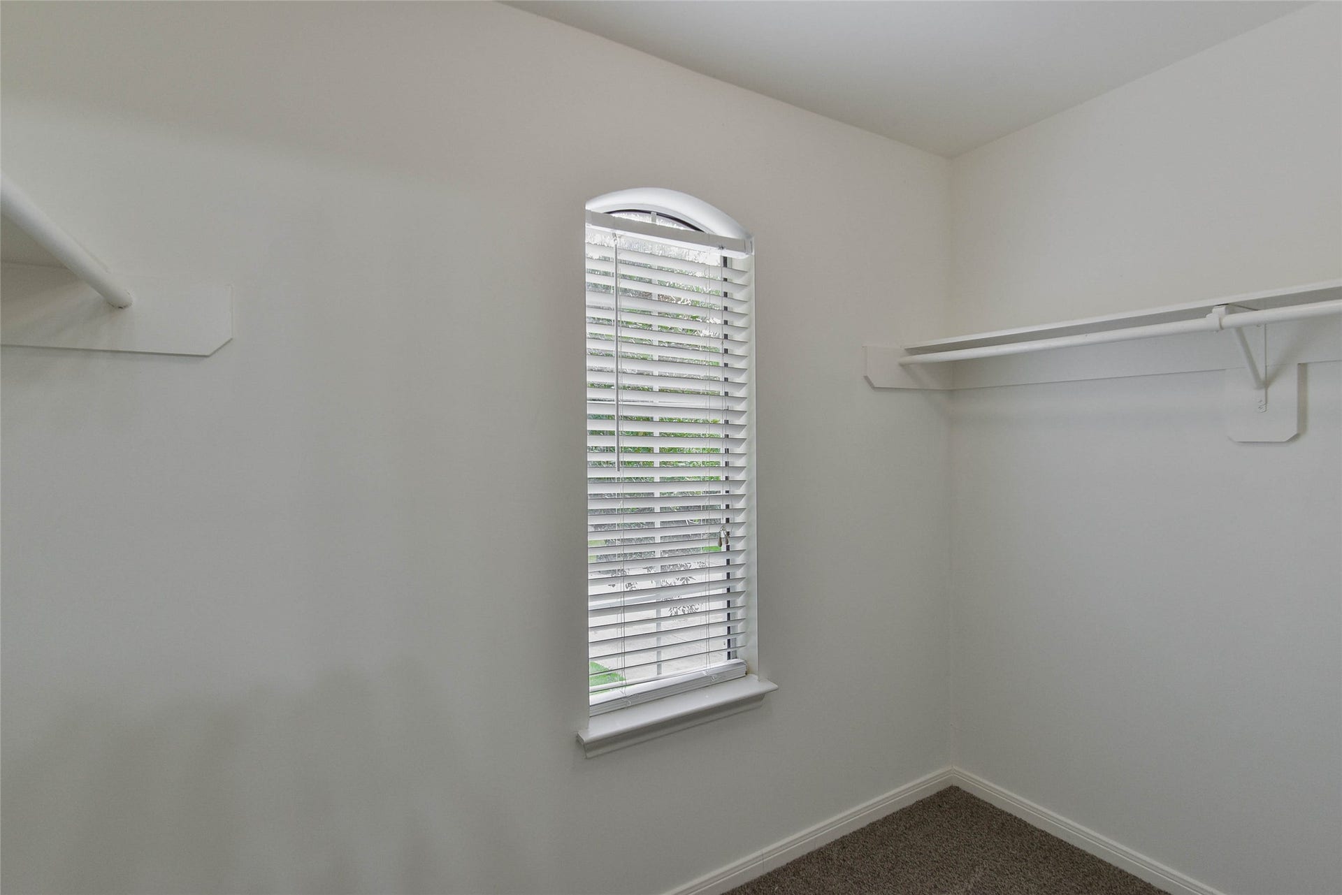 7023 Timber Edge Lane Lane, Humble, TX 77346 Bright and airy walk-in closet featuring ample shelving and a window with blinds for natural light.