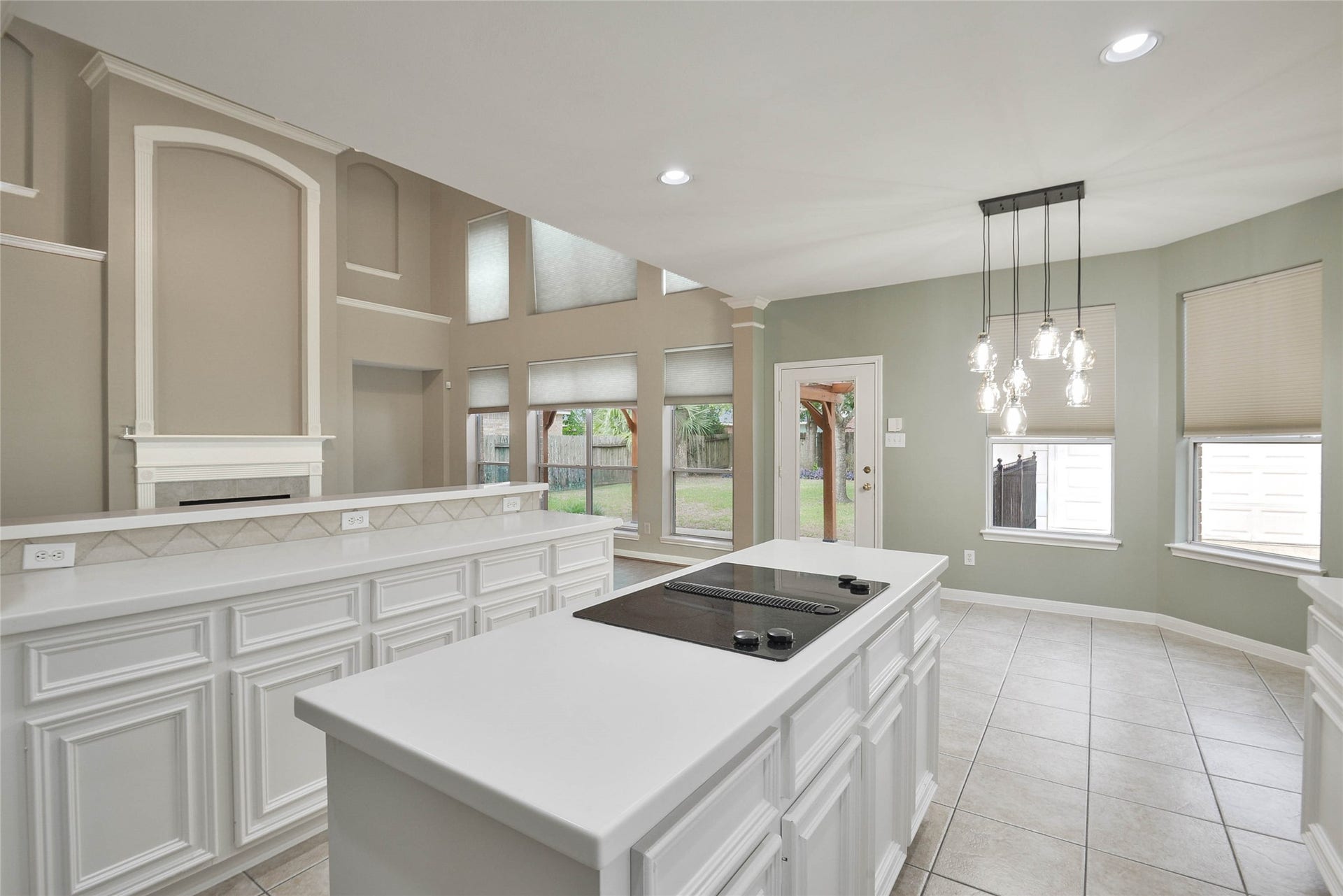 7023 Timber Edge Lane Lane, Humble, TX 77346 Kitchen with modern island cooktop, elegant pendant lighting, and ample natural light from large windows, perfect for culinary adventures and entertaining.