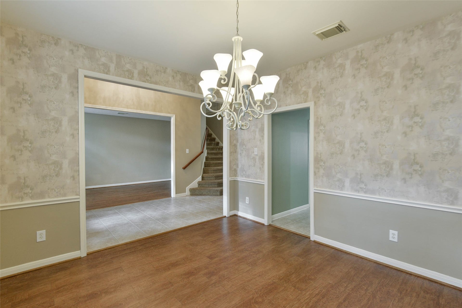 7023 Timber Edge Lane Lane, Humble, TX 77346 Elegant dining room featuring a stylish chandelier, and warm wood flooring, seamlessly connecting to a spacious living area and stairway.