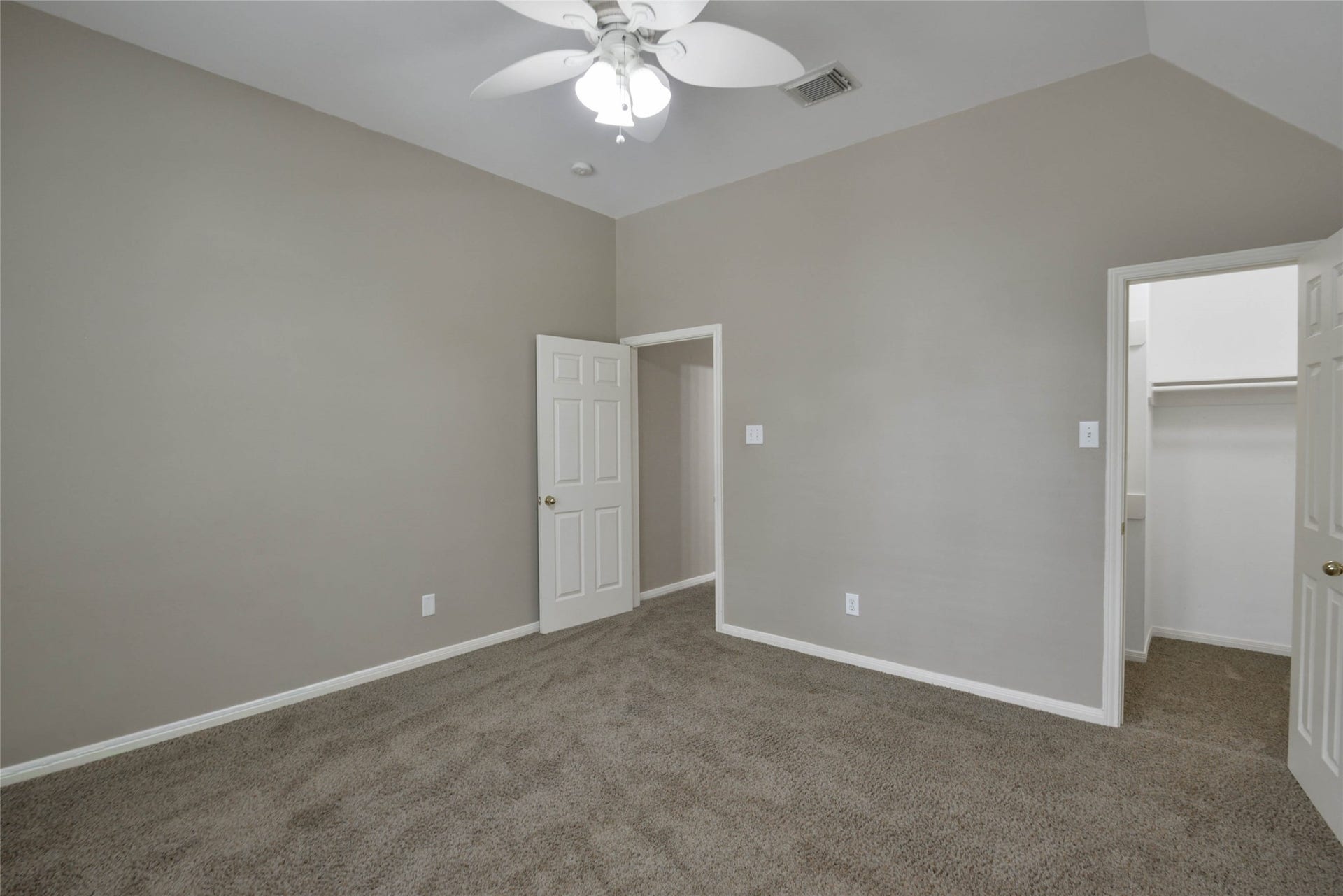 7023 Timber Edge Lane Lane, Humble, TX 77346 Bedroom with plush carpet, neutral walls, and a ceiling fan, featuring an adjoining walk-in closet for ample storage.