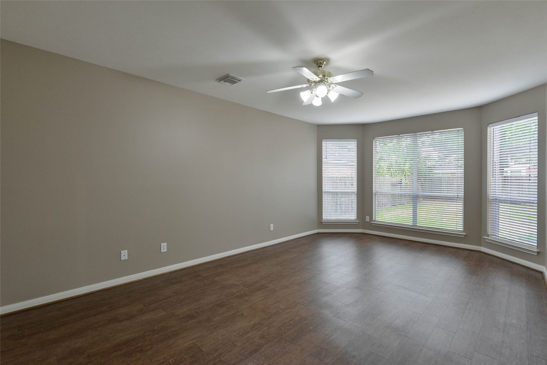 7023 Timber Edge Lane Lane, Humble, TX 77346 Primary bedroom with large windows, wood flooring, and a ceiling fan, offering ample natural light and comfort.