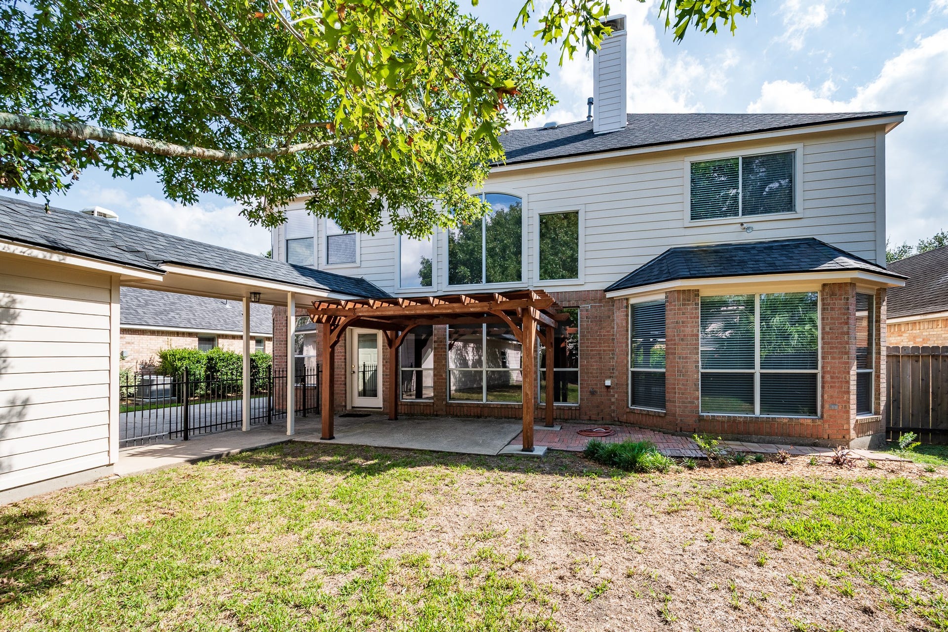 7023 Timber Edge Lane Lane, Humble, TX 77346 Backyard with a charming pergola, ideal for outdoor entertaining, and a well-maintained exterior with large windows for ample natural light.