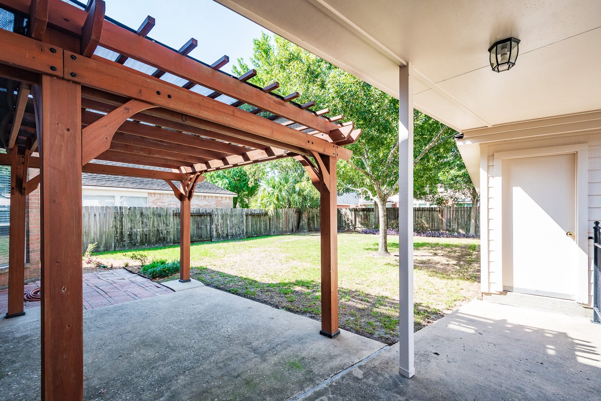 7023 Timber Edge Lane Lane, Humble, TX 77346 Charming backyard with a wooden pergola and covered patio, perfect for outdoor relaxation and entertaining.