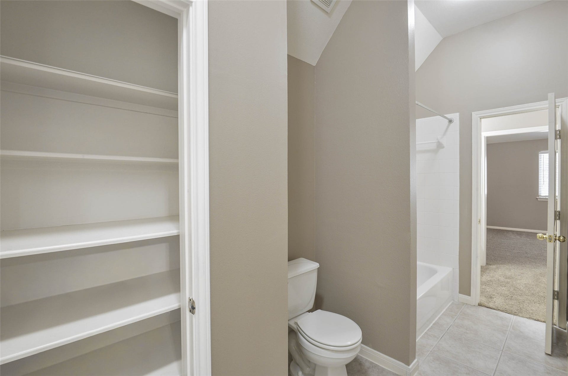 7023 Timber Edge Lane Lane, Humble, TX 77346 Secondary bathroom featuring convenient built-in shelving, a bathtub-shower combo, and easy access to an adjoining carpeted room.
