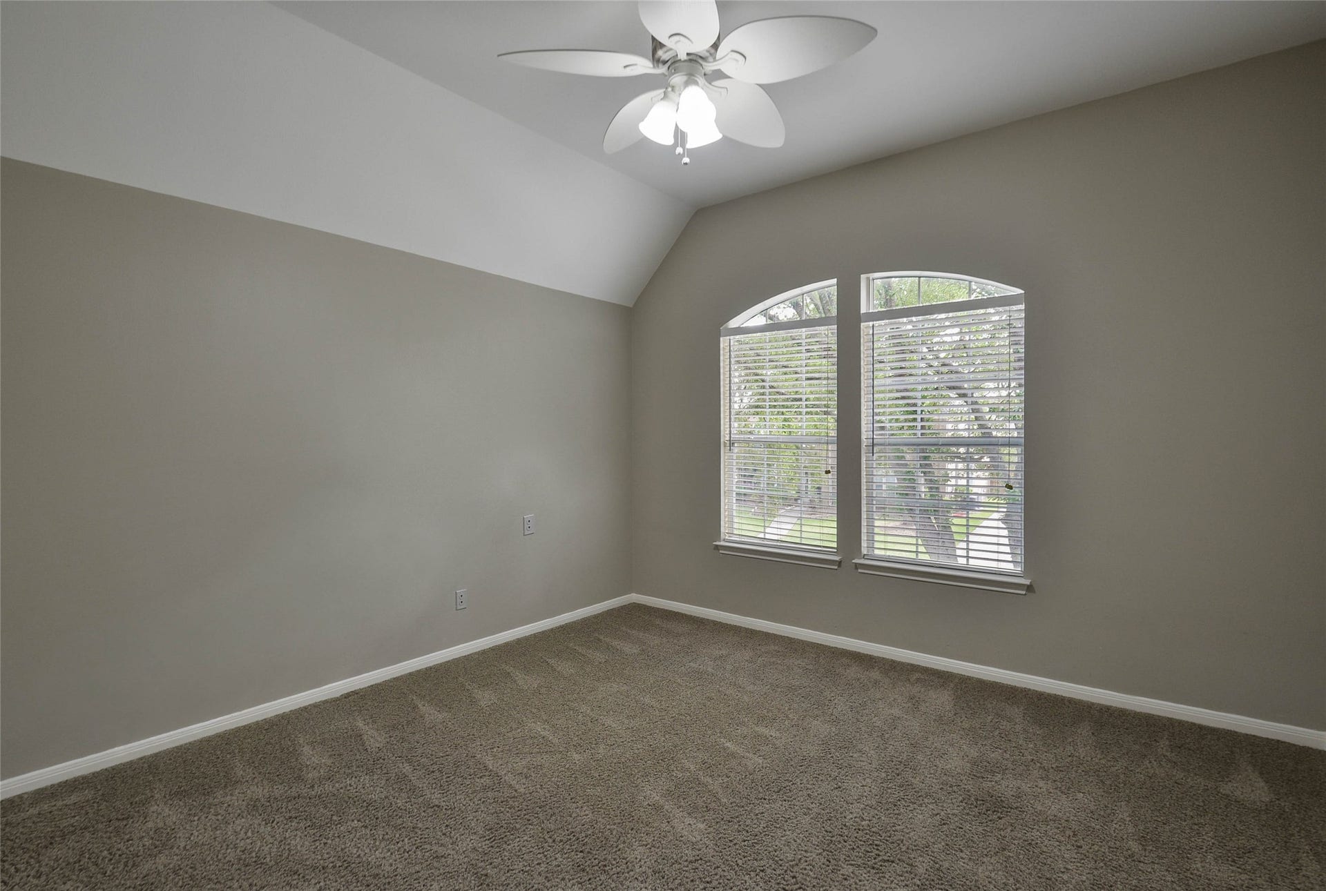 7023 Timber Edge Lane Lane, Humble, TX 77346 Secondary bedroom featuring plush carpet, a vaulted ceiling, and large arched windows that invite natural light.